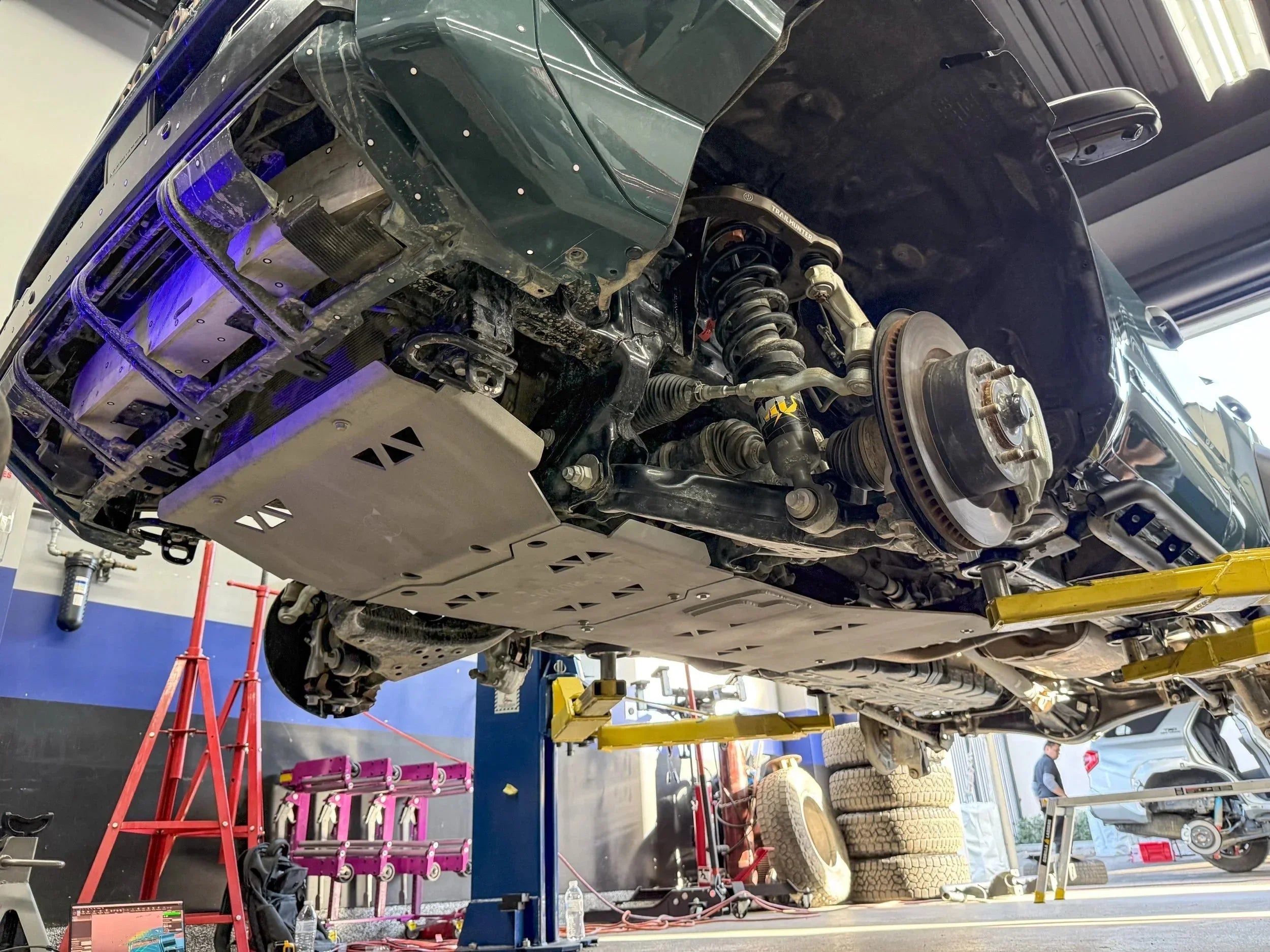 Toyota 4Runner on lift showing skid plate and suspension during off-road upgrade in garage