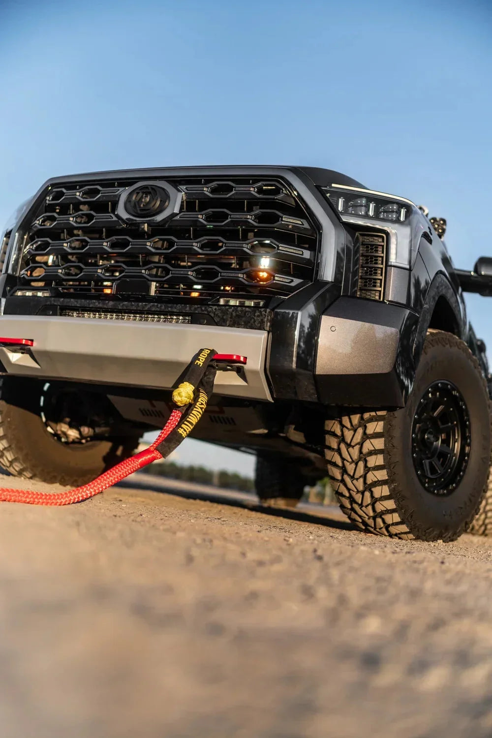 Off-road truck front view with tow strap attached, rugged tires, ready for overlanding adventure