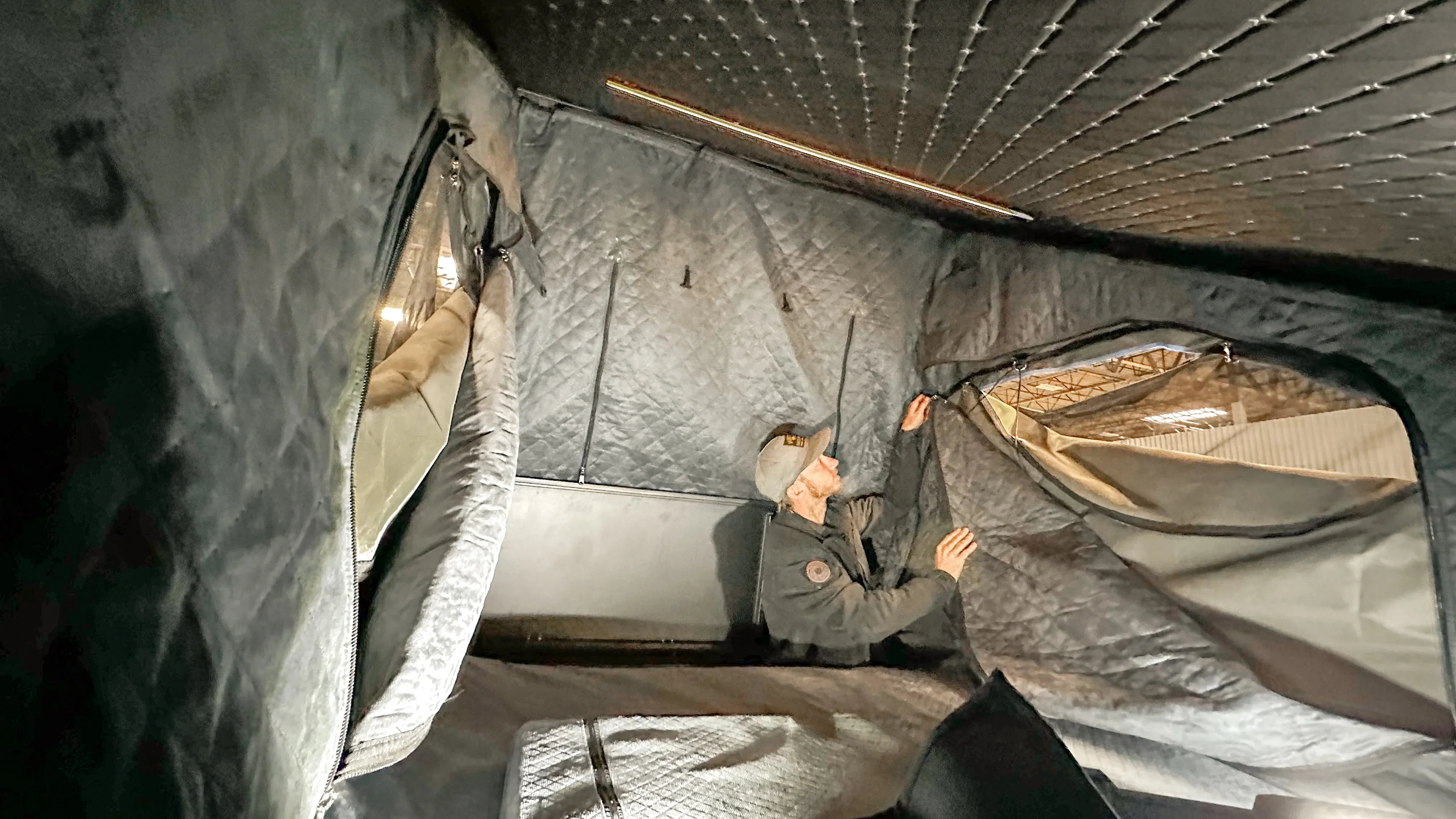 Person installing quilted canopy camper insulation kit inside expedition vehicle tent