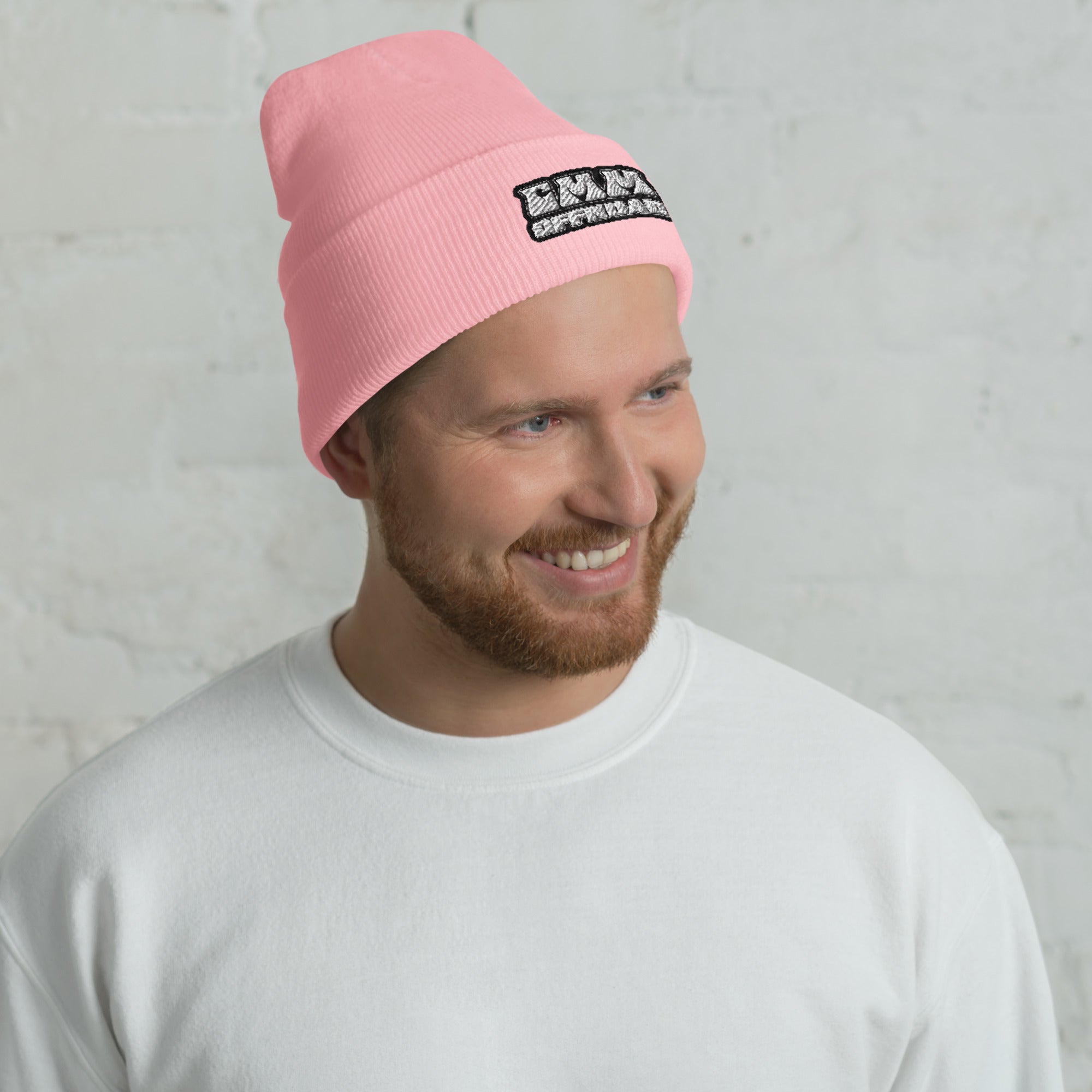 Man wearing a baby pink cuffed beanie with a patch logo, casual white sweatshirt