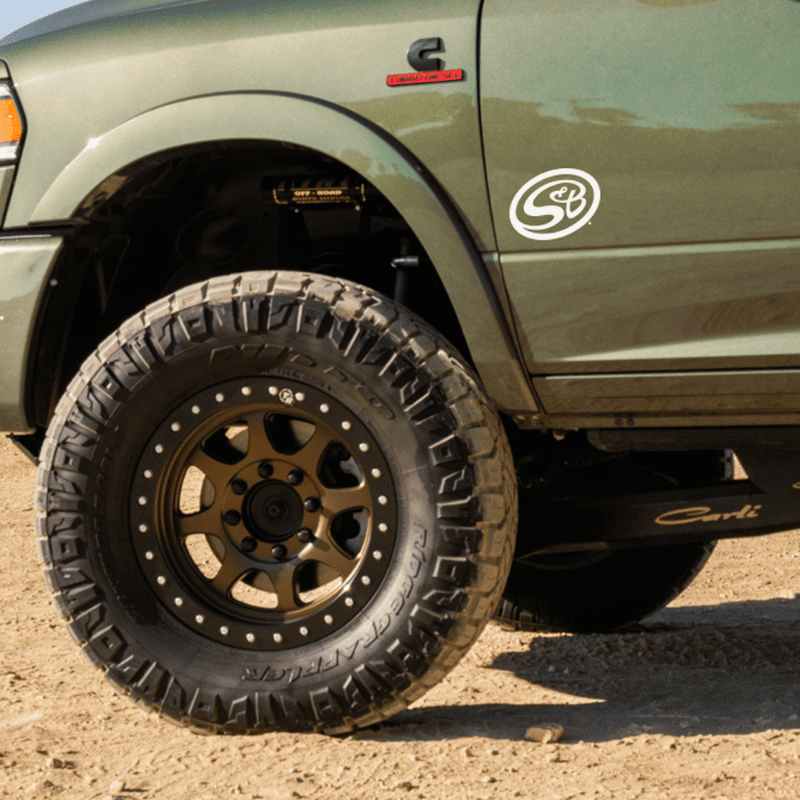 A green truck with a decal of S&B logo on the fender.