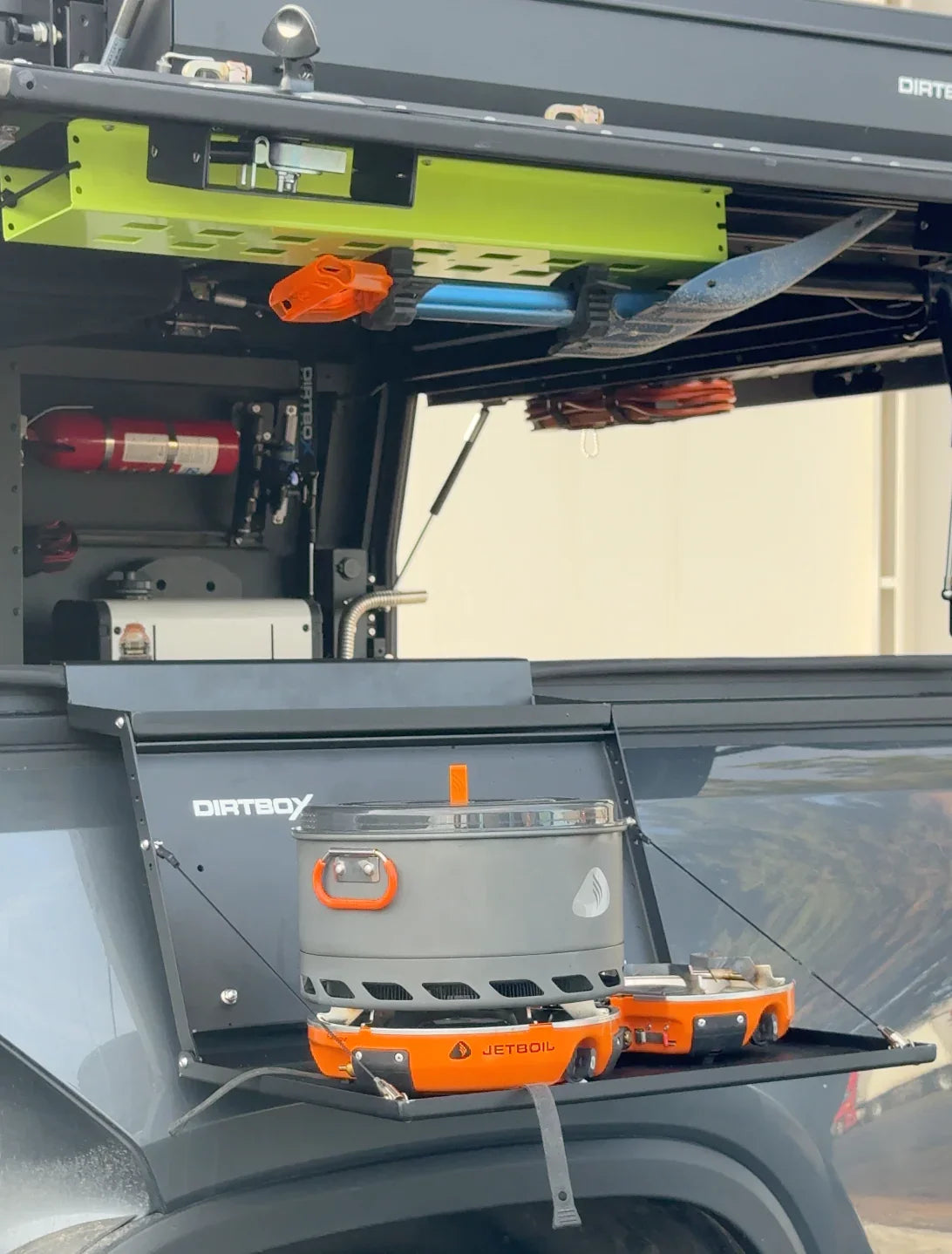 Overland vehicle storage setup with DirtBox hitch table and Jetboil camping stove