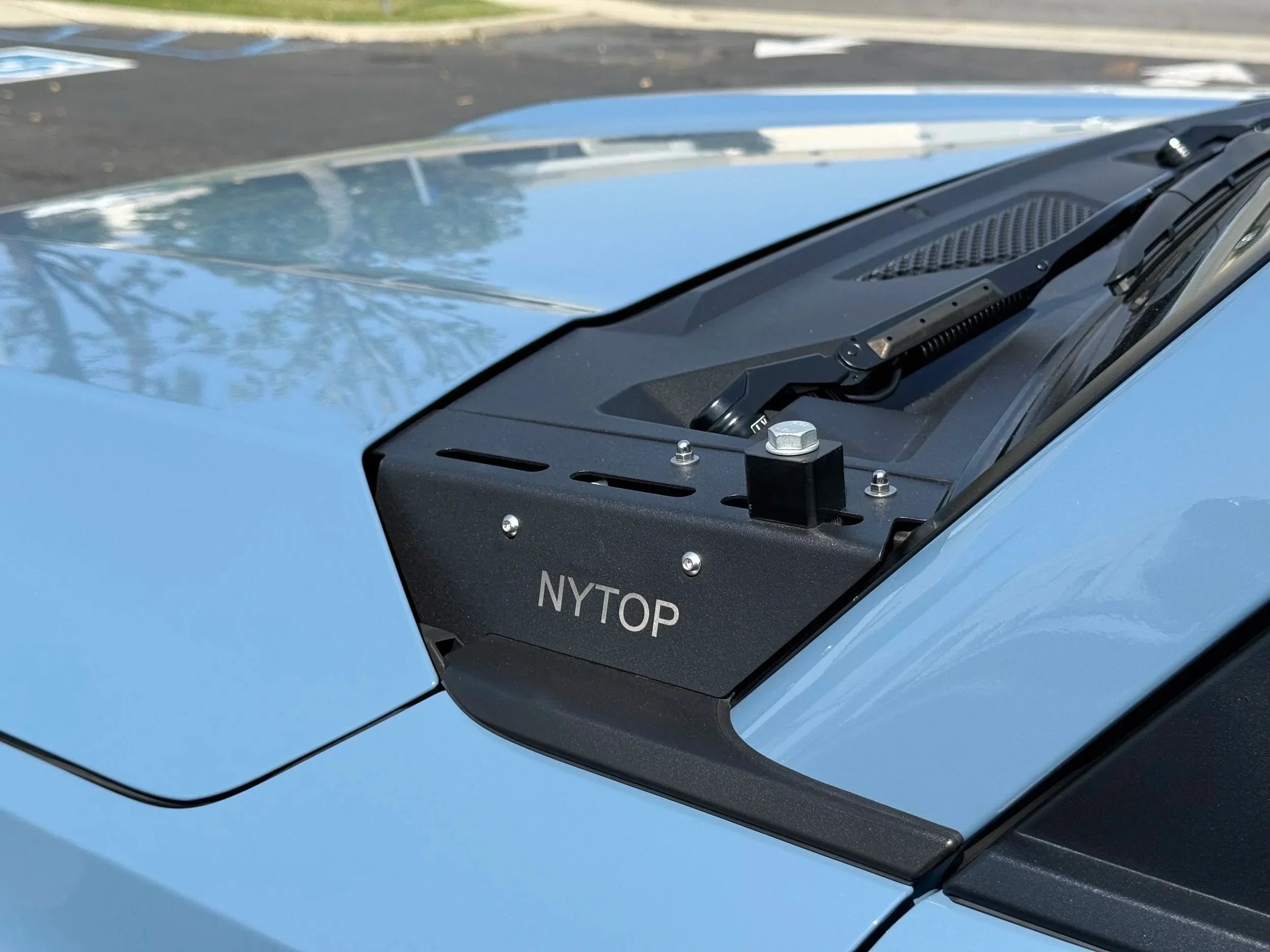 Close-up of NYTOP cowl accessory mounted on a light blue Toyota truck hood