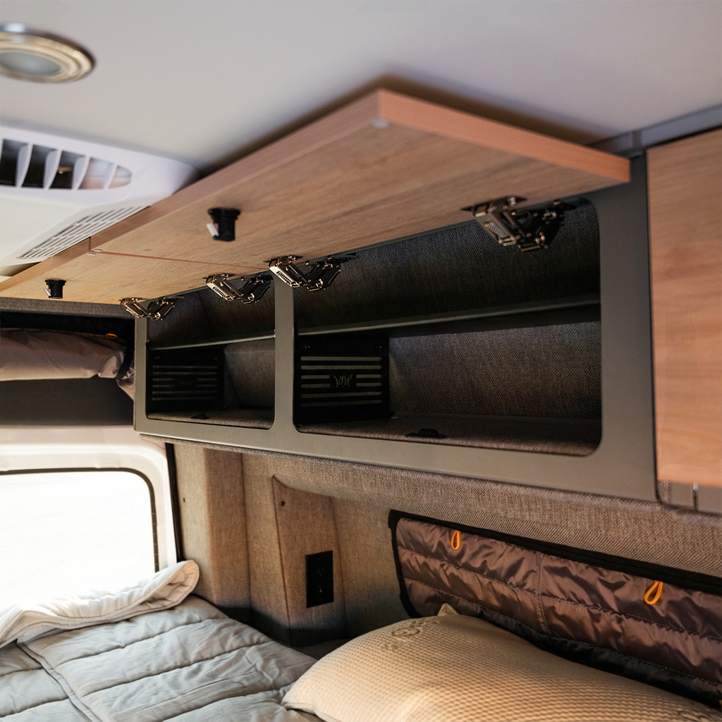 Overland vehicle interior with wood overhead storage cabinets and sleeping area