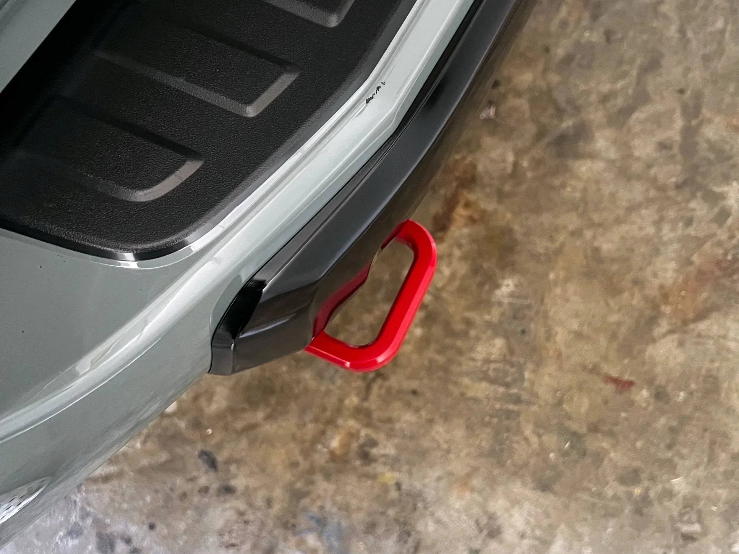 Close-up of a red rear recovery hook mounted on an off-road vehicle bumper