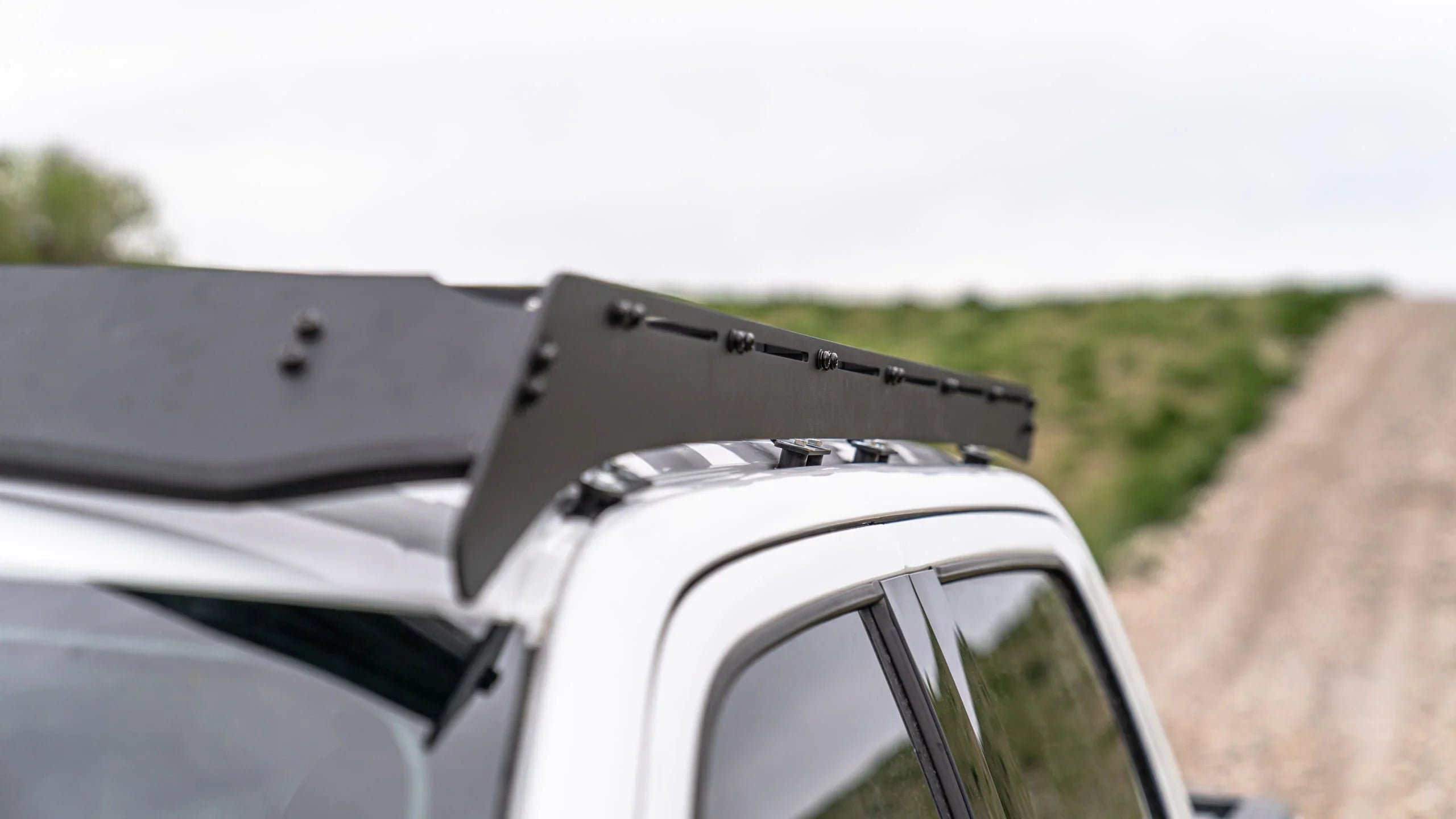 Close-up of black roof rack mounted on white truck, outdoor overlanding accessory