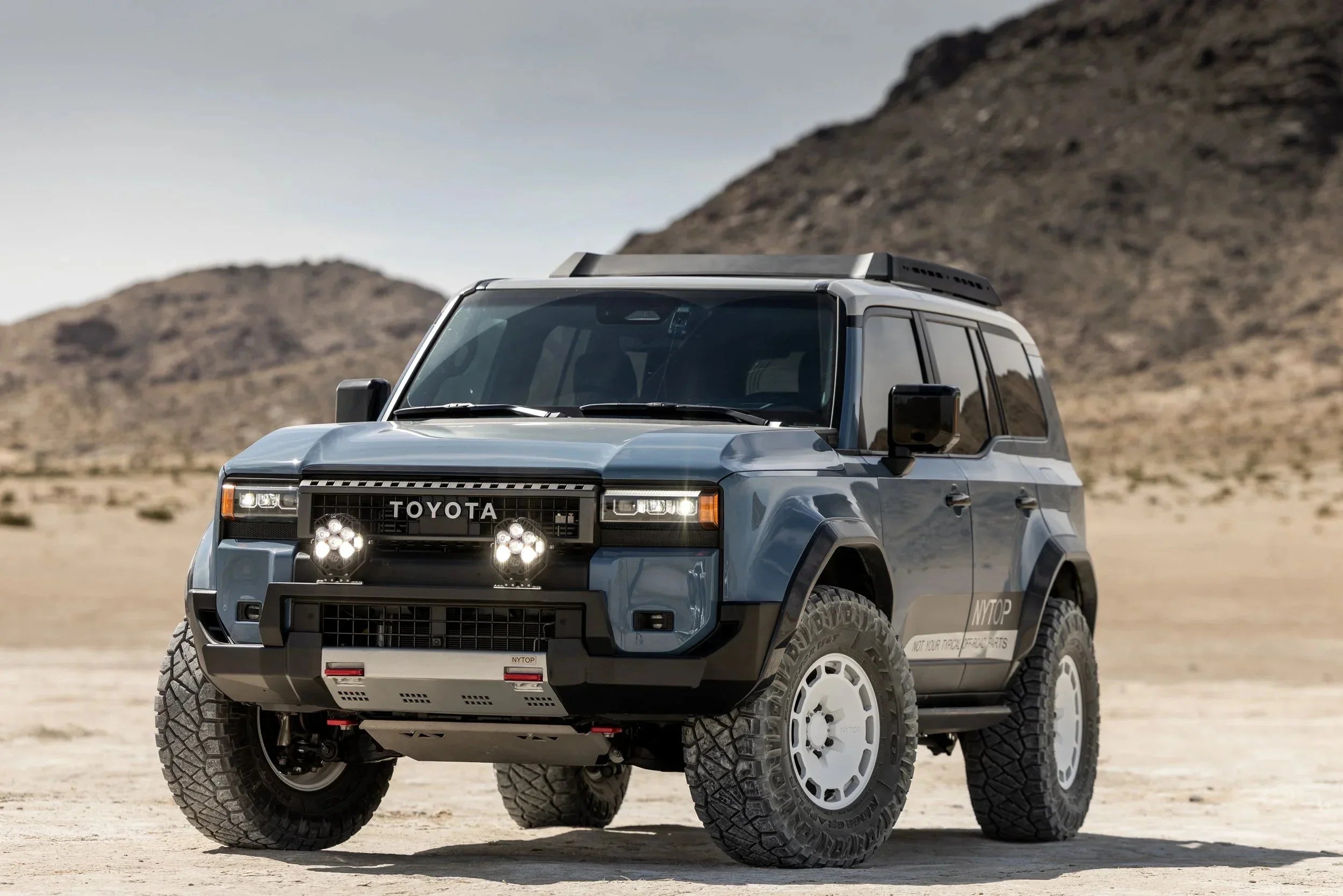 Toyota SUV with off-road accessories and large tires parked in desert landscape