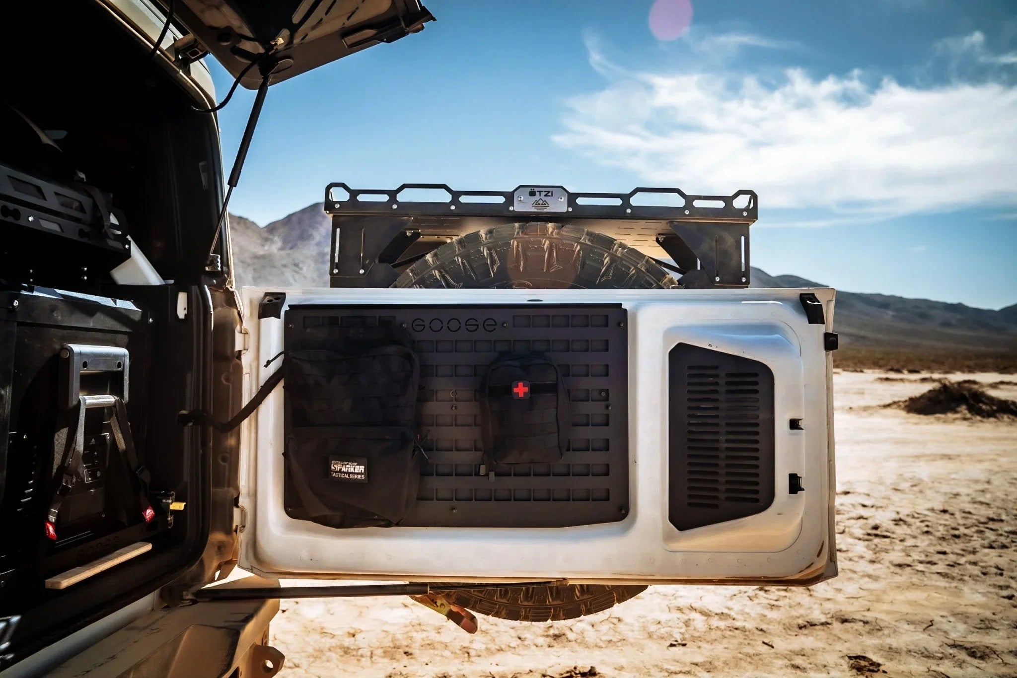 Ford Bronco tailgate MOLLE panel with mounted gear bags in desert landscape