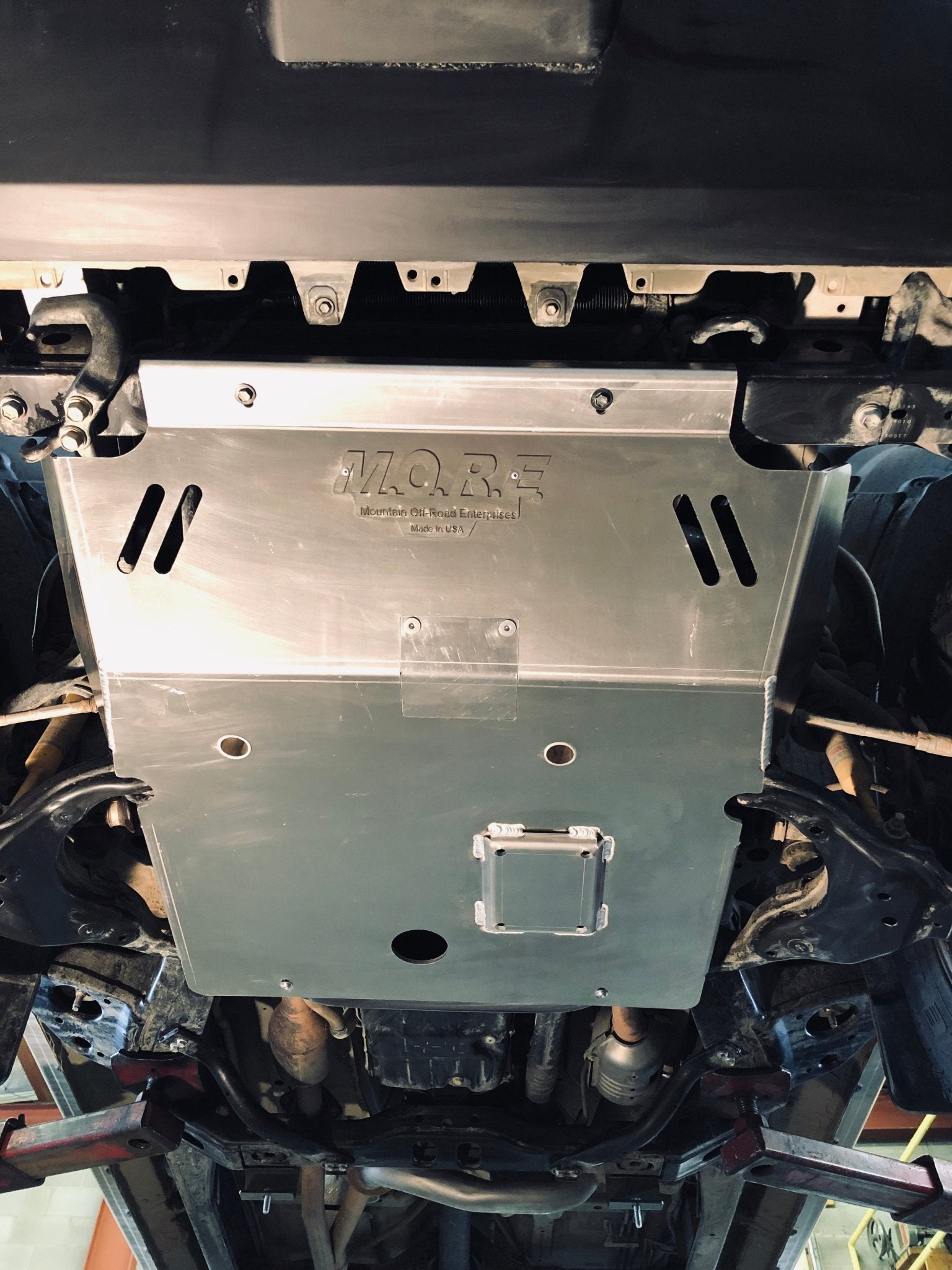 Aluminum front skid plate installed under Toyota Tacoma, underside view, off-road protection