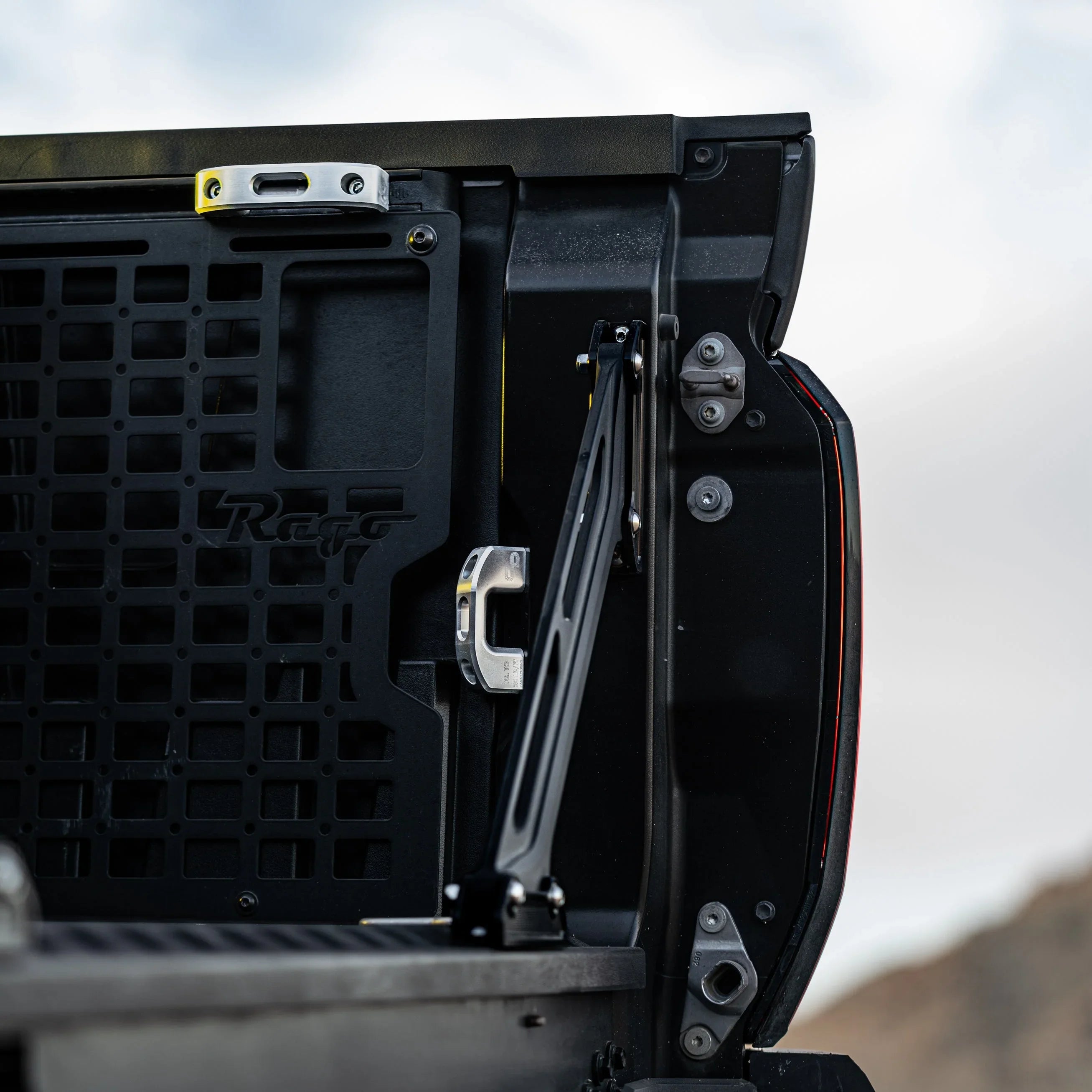 Truck tailgate with black steel molle storage panel and rugged accessory mount outdoors