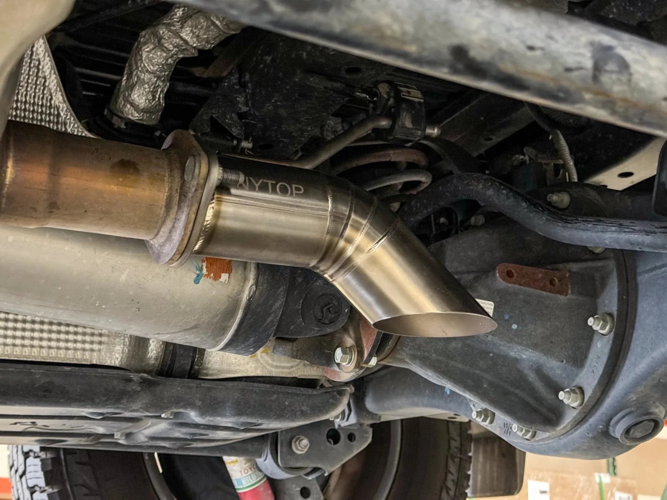 Aftermarket stainless steel exhaust tip installed on off-road vehicle undercarriage