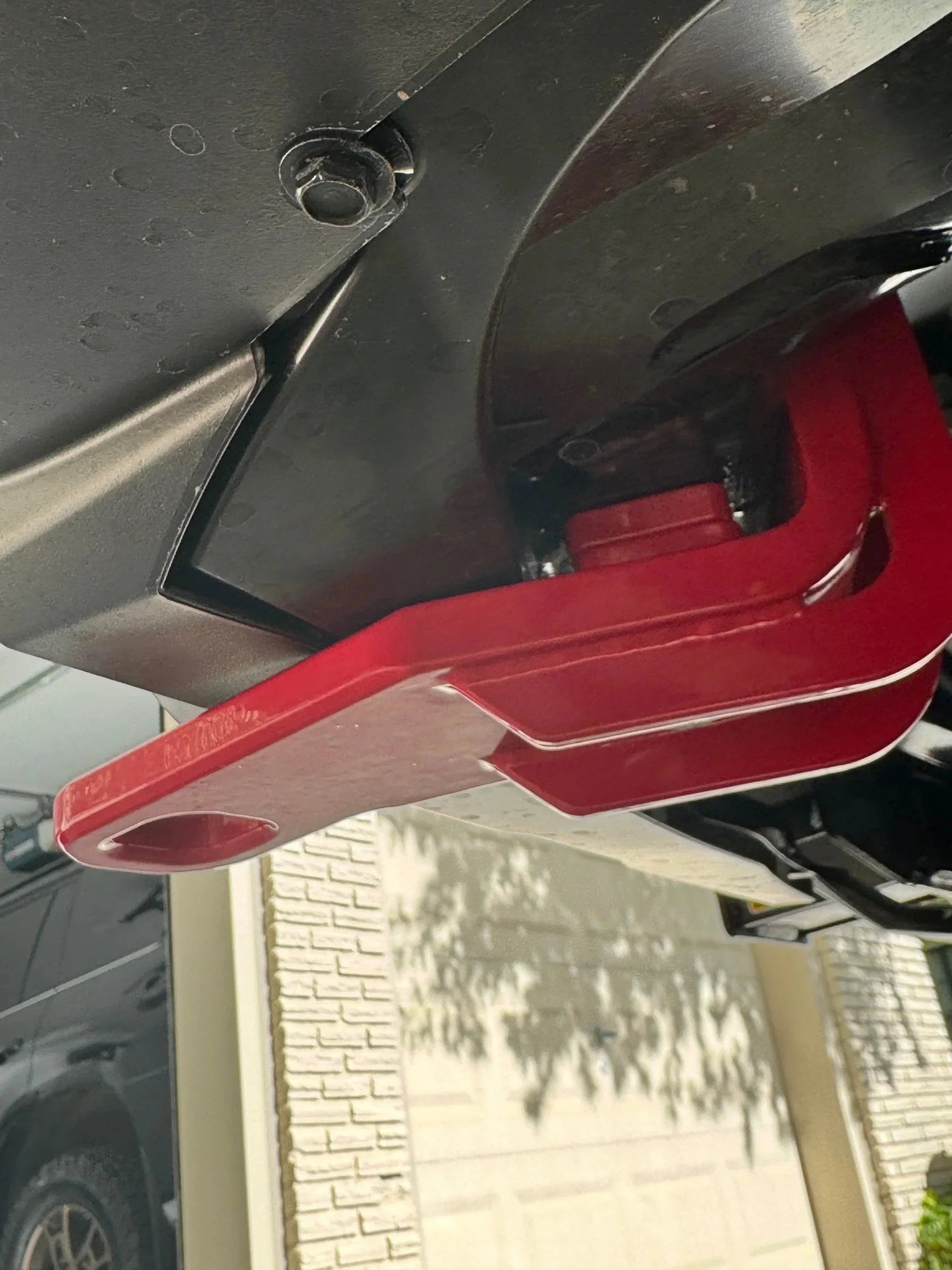 Red steel recovery tow hook mounted on vehicle bumper for overlanding accessory