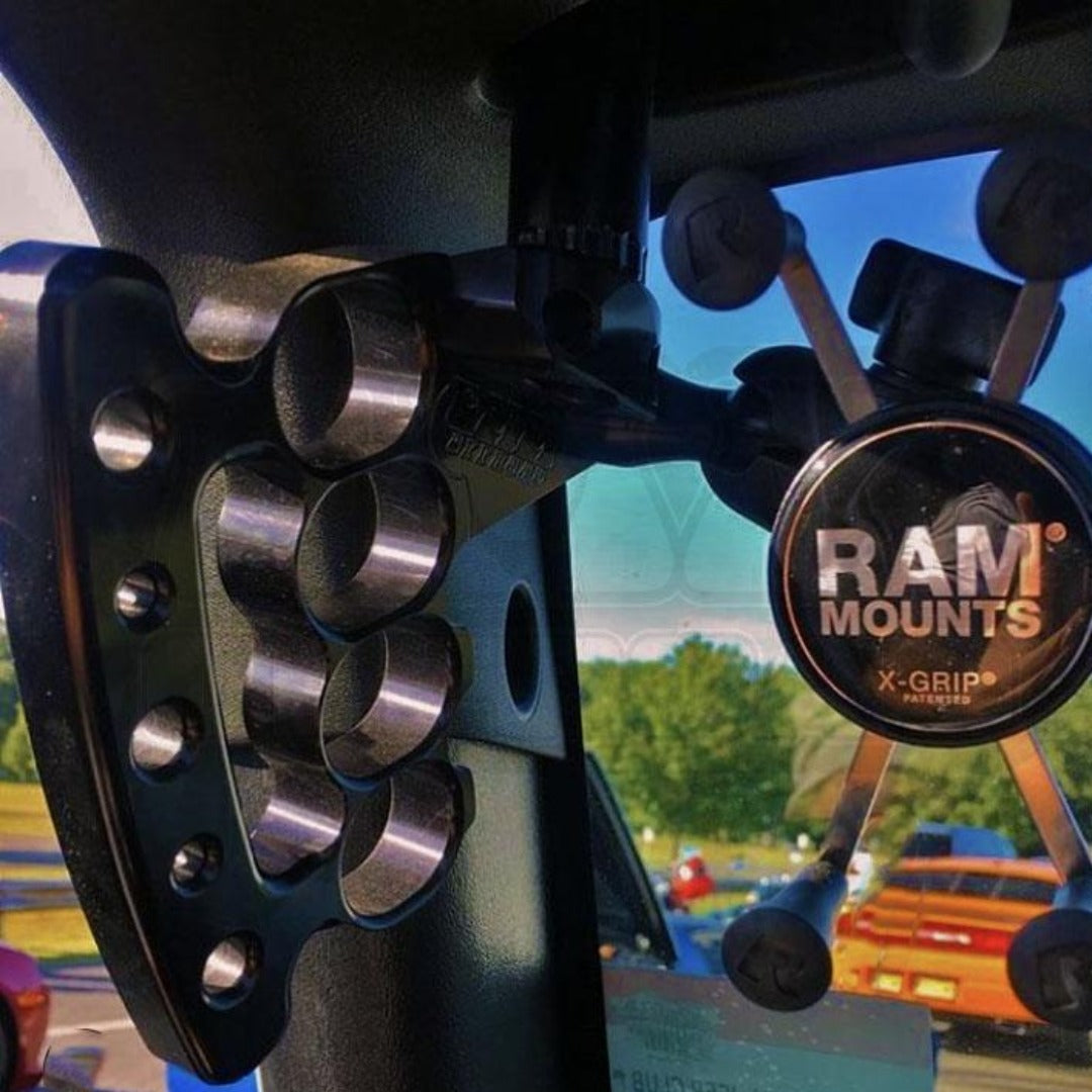 RAM Mounts X-Grip phone holder mounted inside a vehicle with metallic bracket and outdoor view