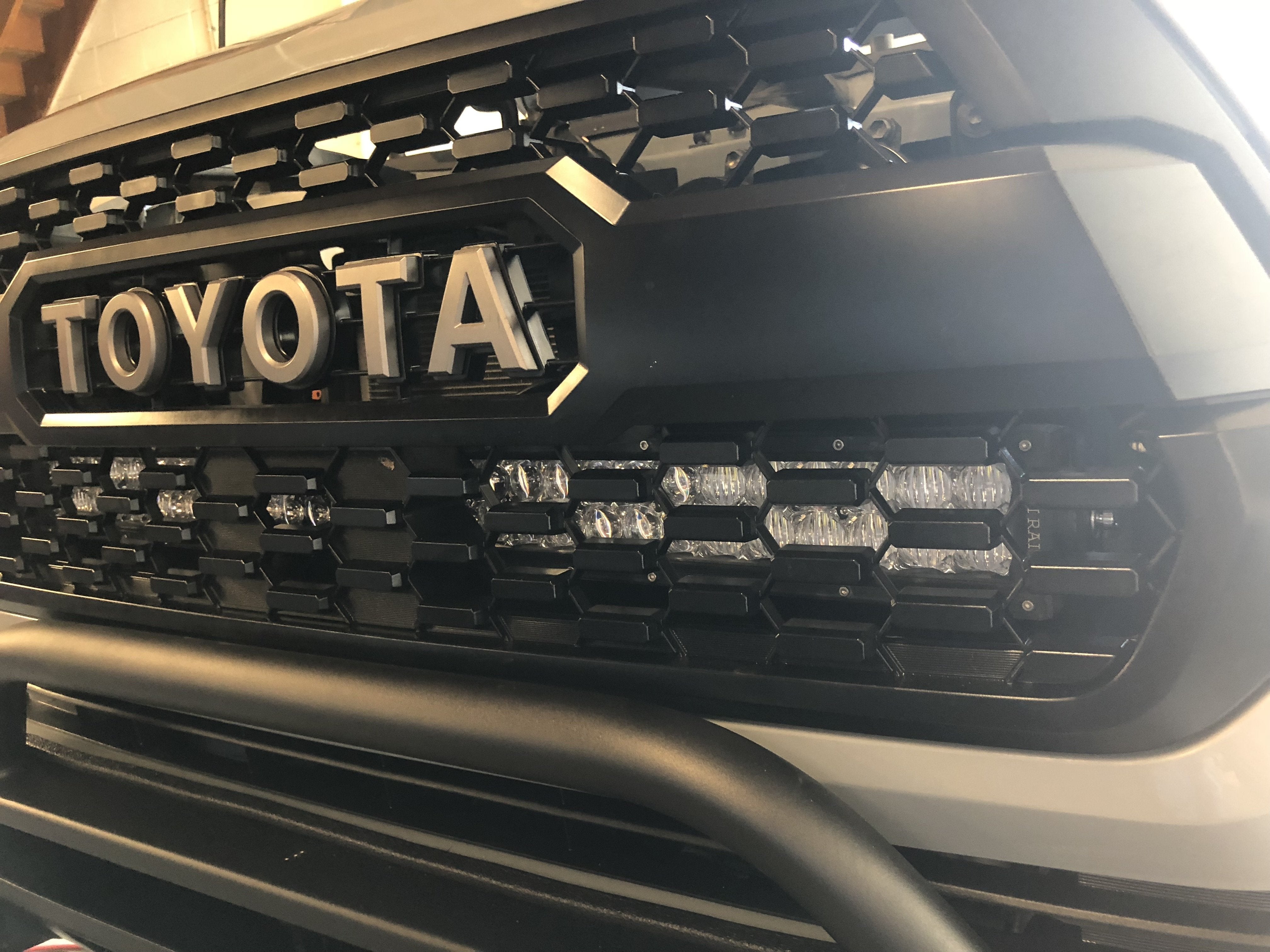 Close-up of Toyota Tacoma front grille with integrated LED light bar.