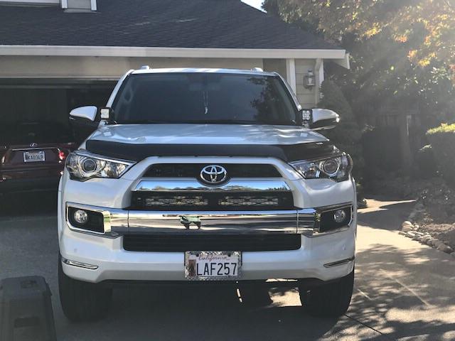 Front view of a white Toyota 4Runner SUV parked in a driveway, outdoors in daylight.