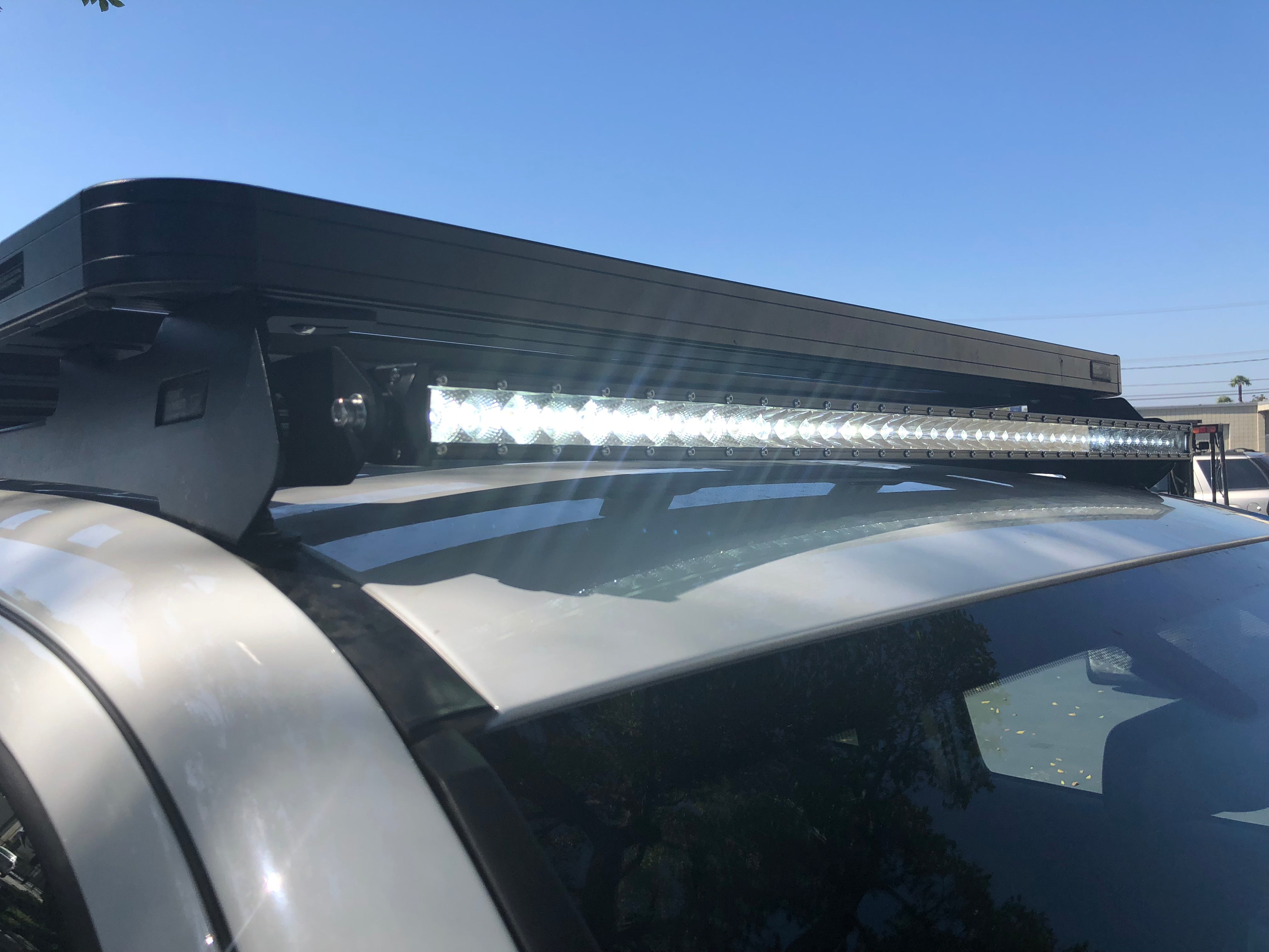 LED light bar mounted on roof rack of off-road vehicle under clear blue sky