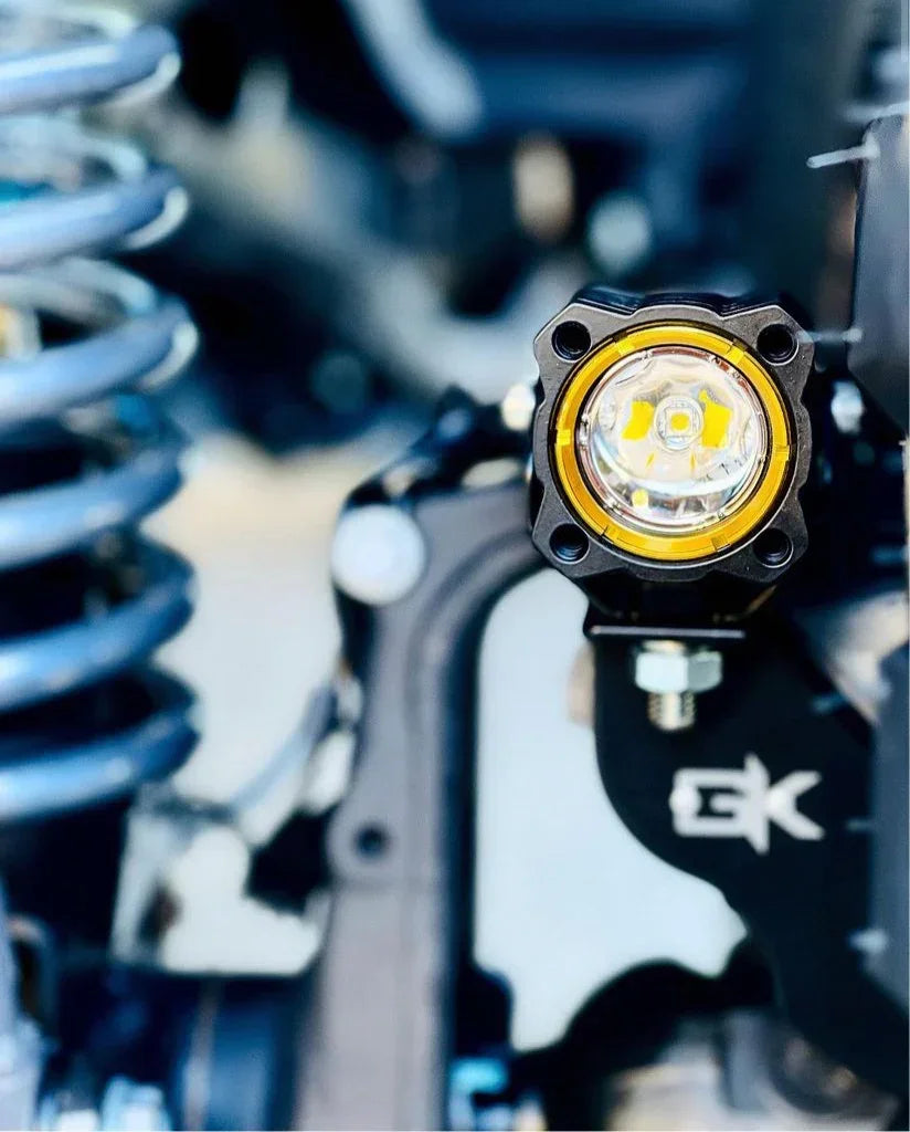 Off-road LED fog light mounted on vehicle suspension with spring and metal parts visible