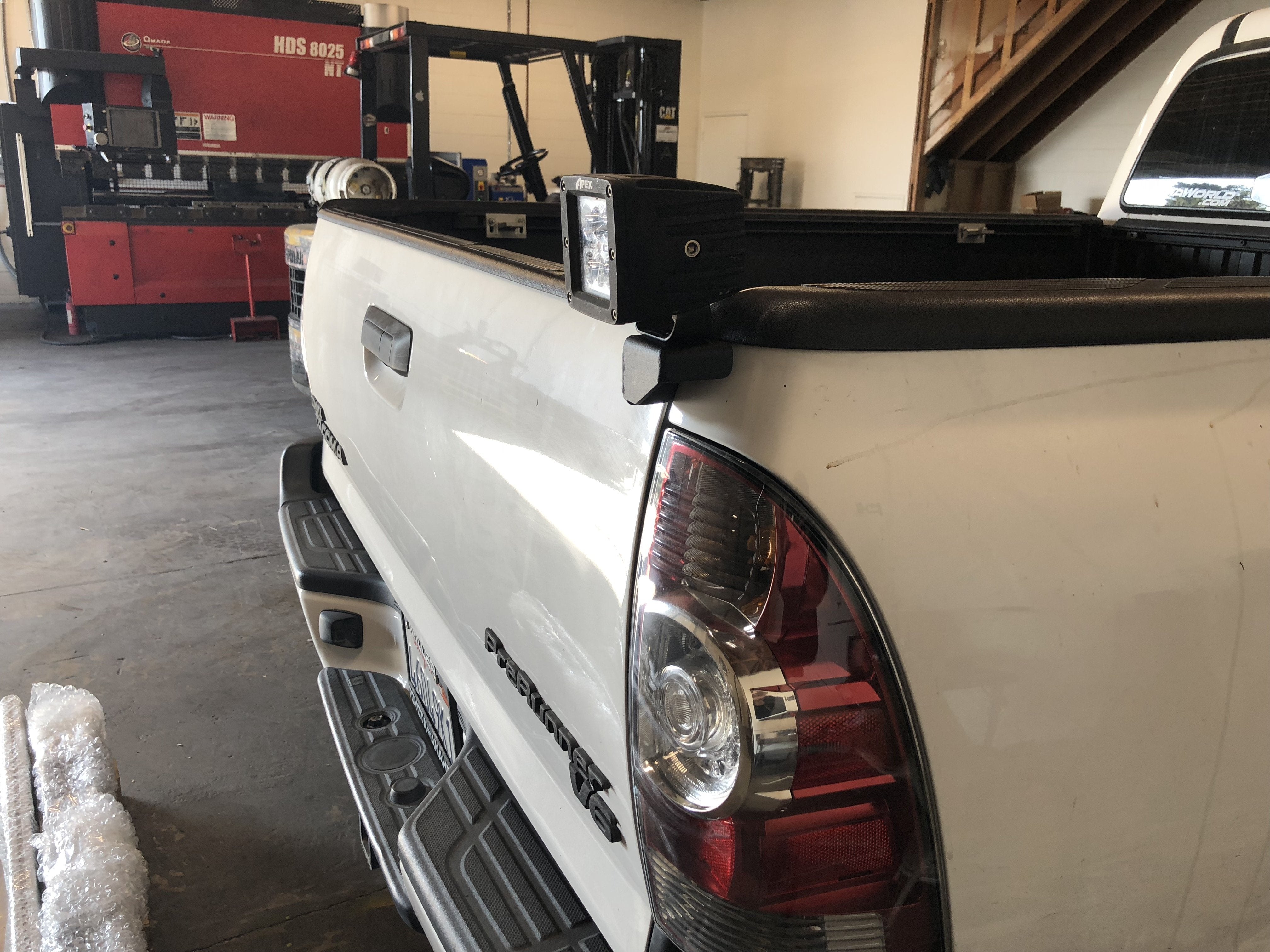 Toyota Tacoma truck bed with aftermarket LED work light installed in a workshop