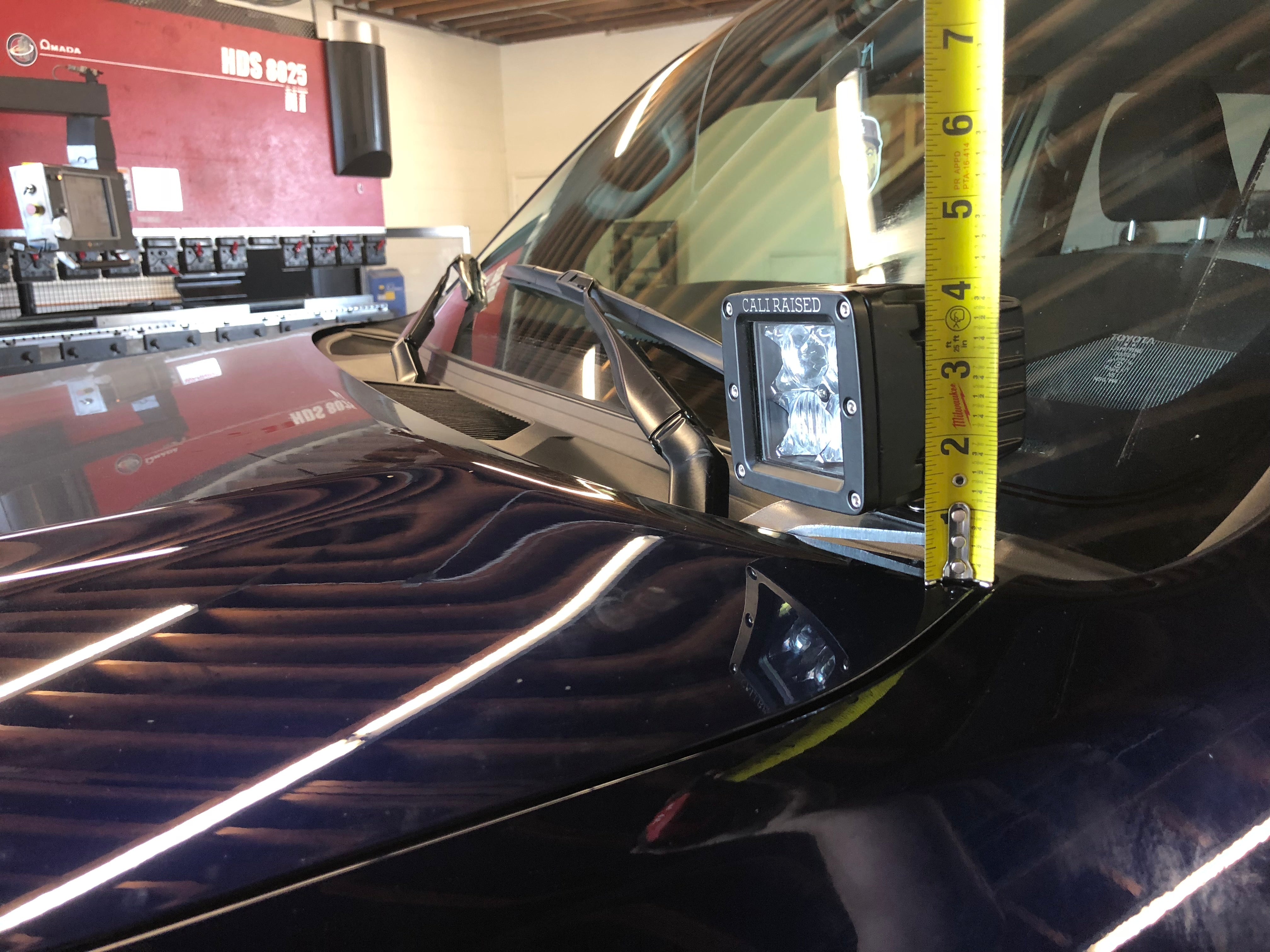 Off-road hood-mounted LED light pod with tape measure on vehicle windshield cowl