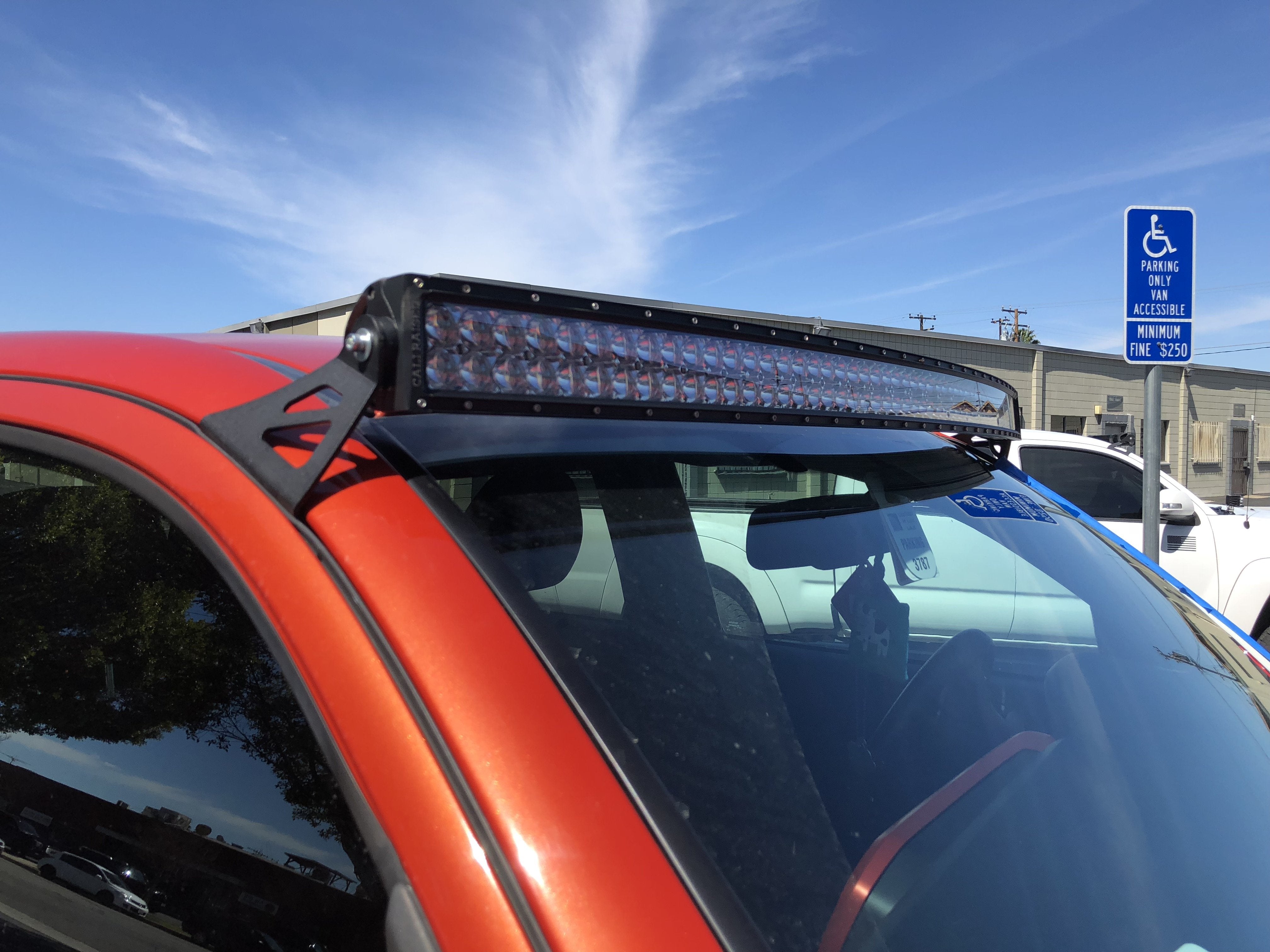 LED light bar mounted on orange off-road vehicle roof, outdoor daylight setting