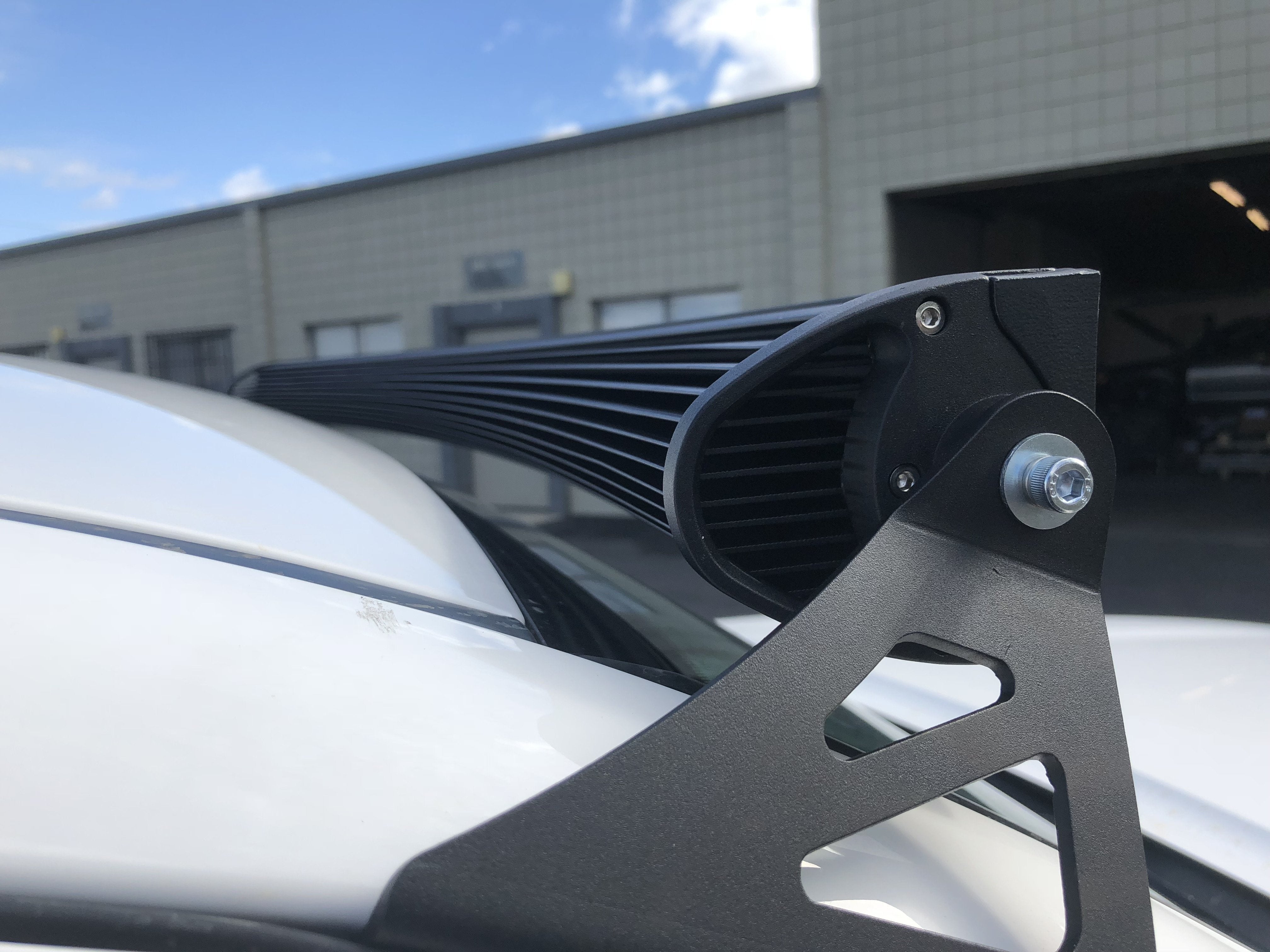 Close-up of black roof rack or light bar mount on white overlanding vehicle