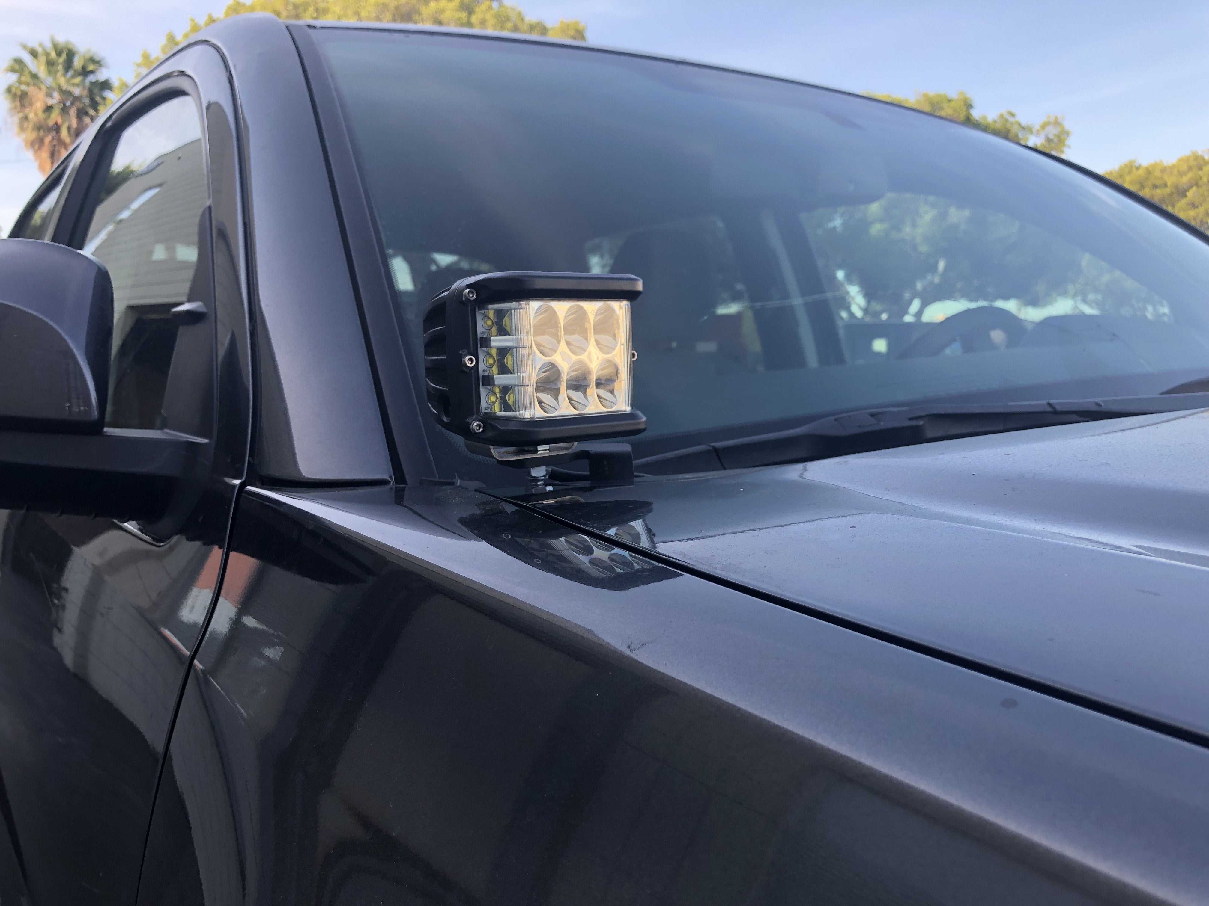 Close-up of off-road LED ditch light installed on black Tacoma truck hood