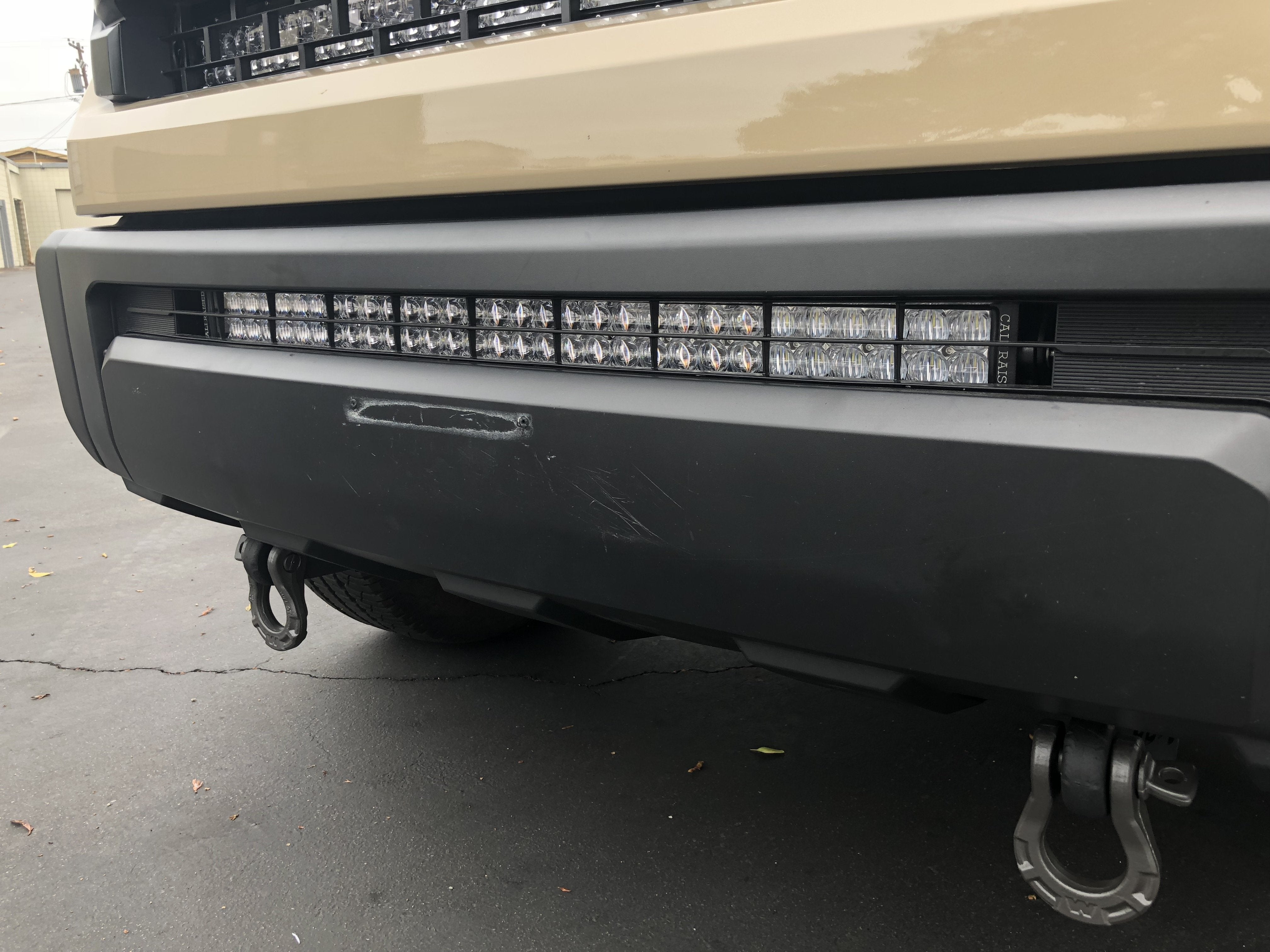 Closeup of off-road vehicle bumper with integrated LED light bar and recovery hooks