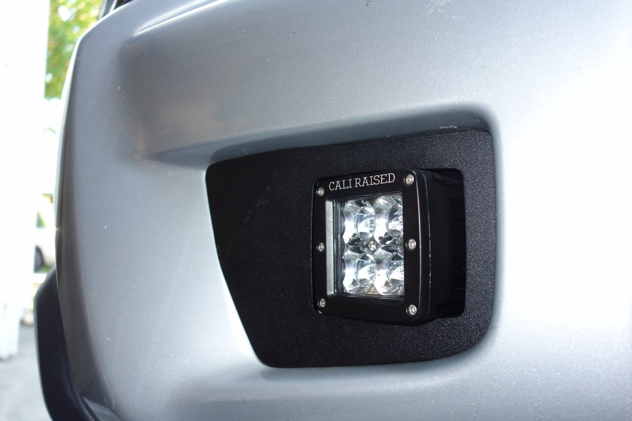 Cali Raised off-road LED fog light installed on a vehicle bumper, close-up view.