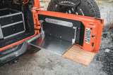Goose Gear tailgate table folded down on an orange Jeep Wrangler JL, metal work surface and bamboo extension at the tailgate