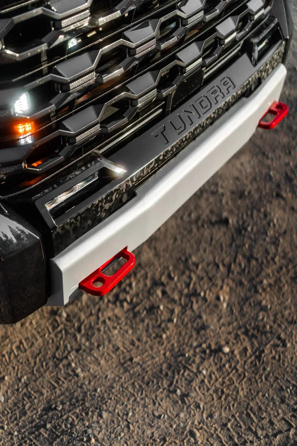 Toyota Tundra front bumper with red recovery tow hooks on rugged terrain