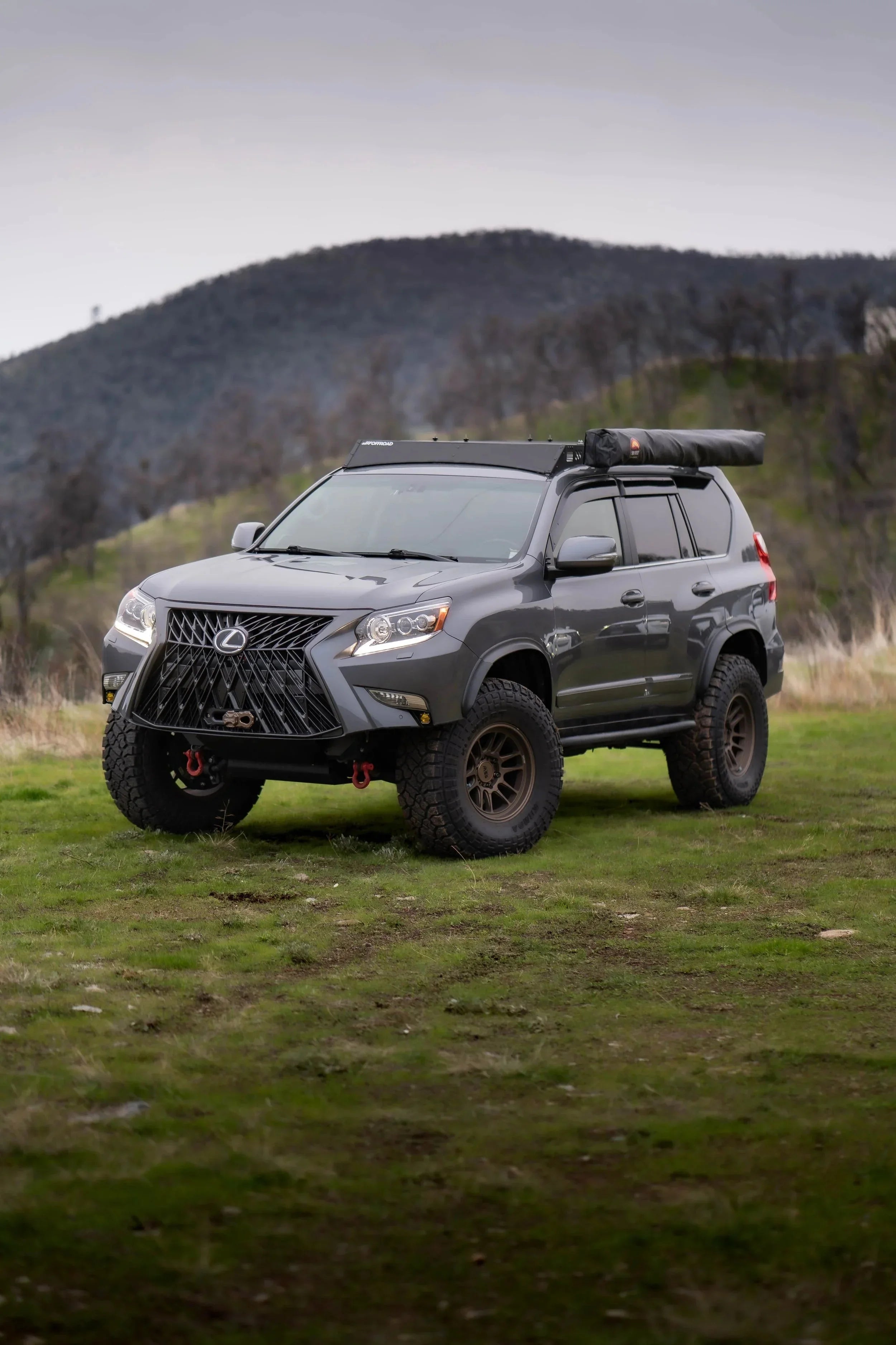 Lifted Lexus GX overland SUV with roof rack and awning on grassy outdoor trail