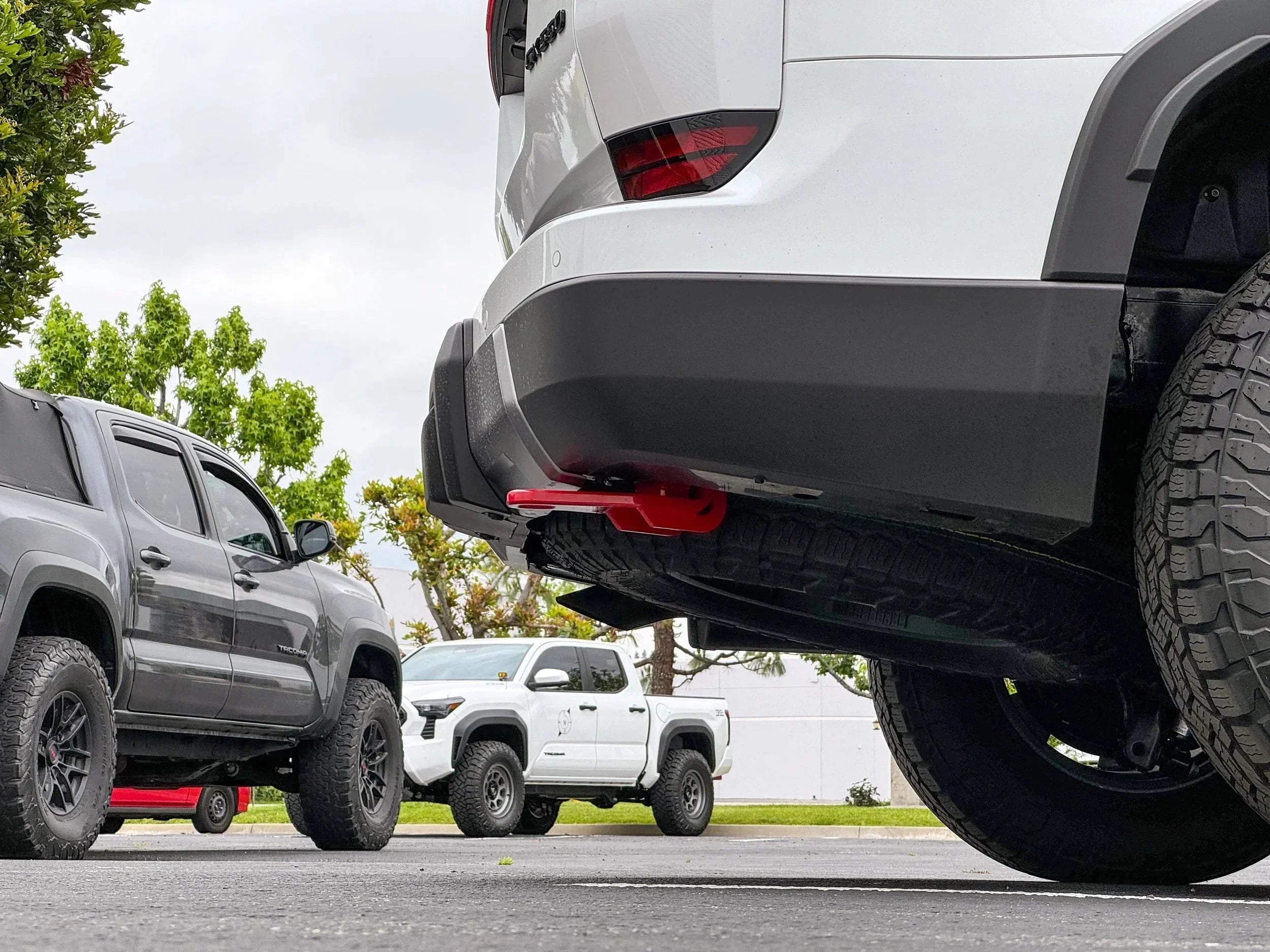 Toyota truck rear bumper with red recovery point, off-road tires, and overland gear