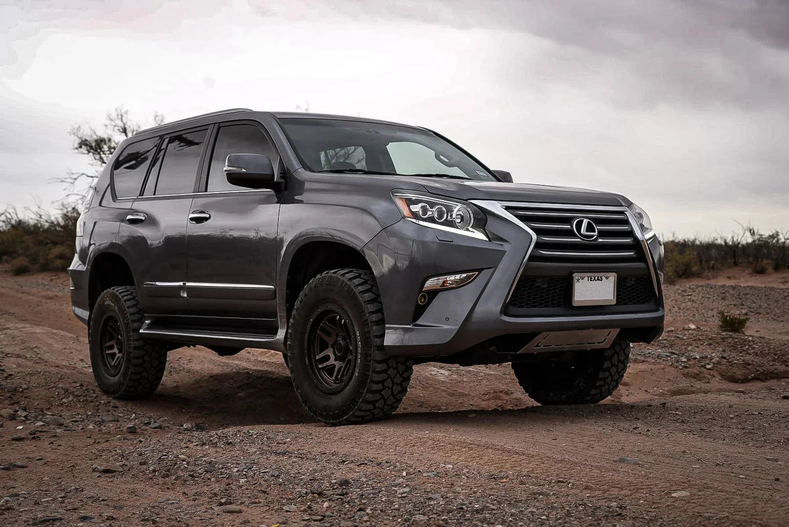 Lifted Lexus SUV with off-road tires parked on a rugged desert trail, overland adventure vehicle