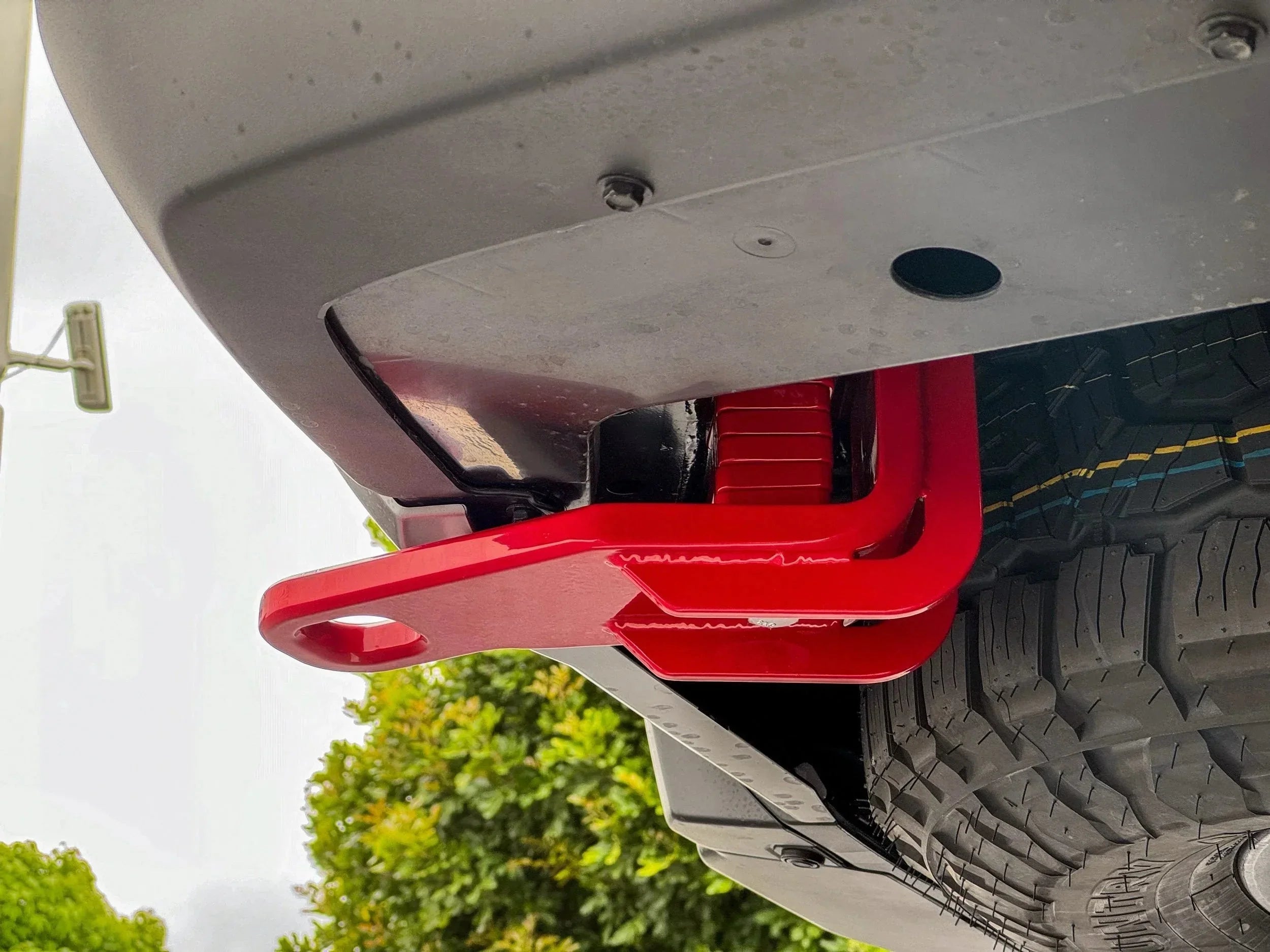 Red tow recovery point mounted on rear of off-road vehicle with all-terrain tire