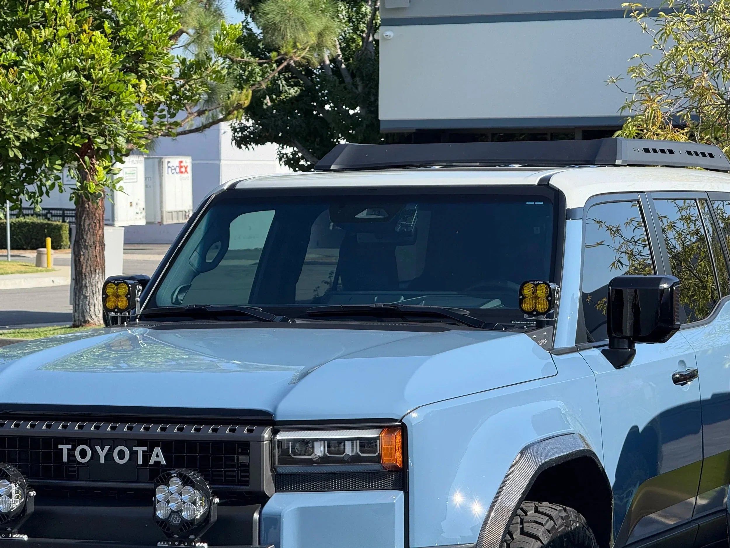 Light blue Toyota SUV with off-road lights and roof rack in outdoor setting