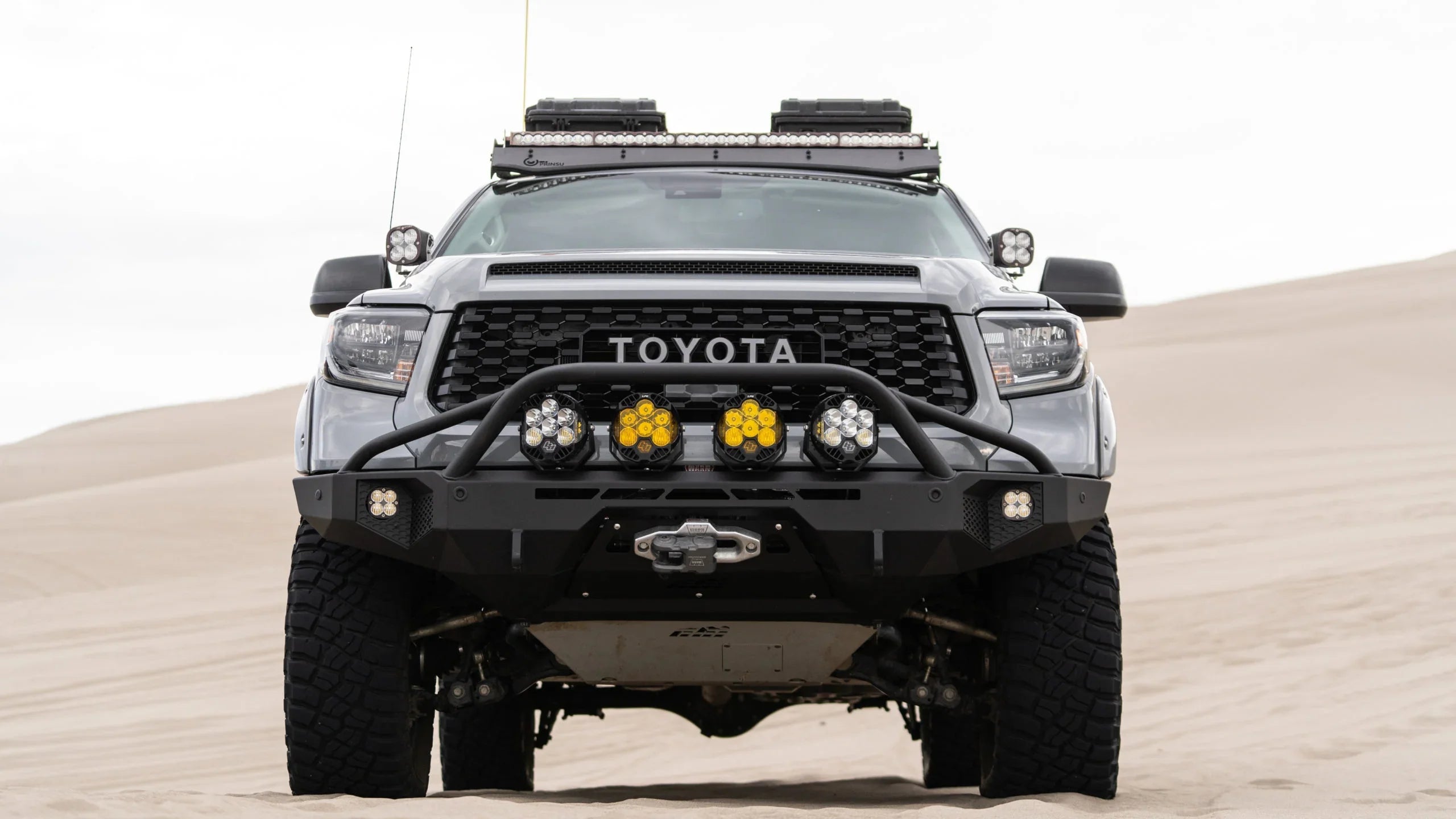 Lifted Toyota truck with off-road lights and accessories parked on sand dunes