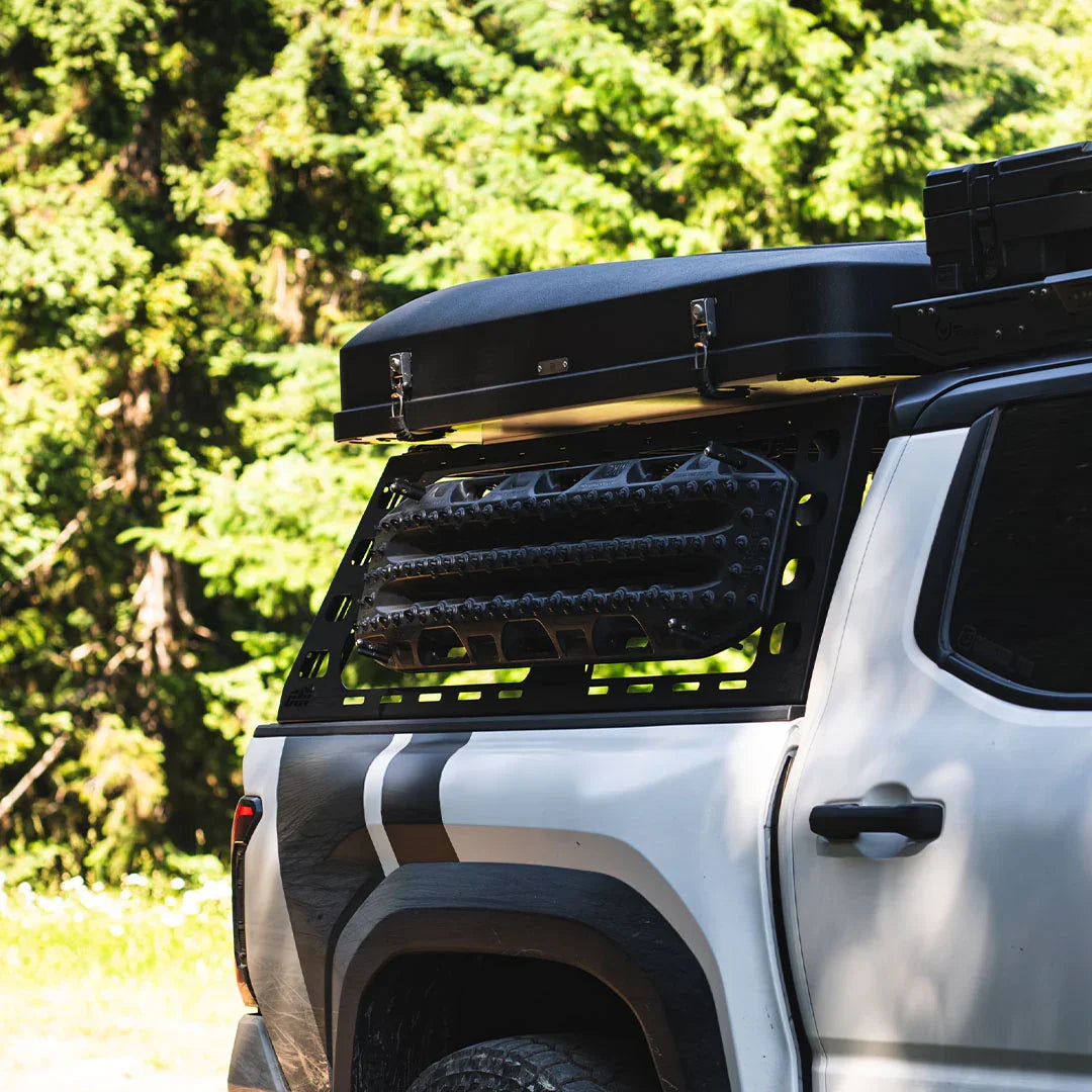 Overlanding bed rack with rooftop cargo box and recovery boards on adventure vehicle