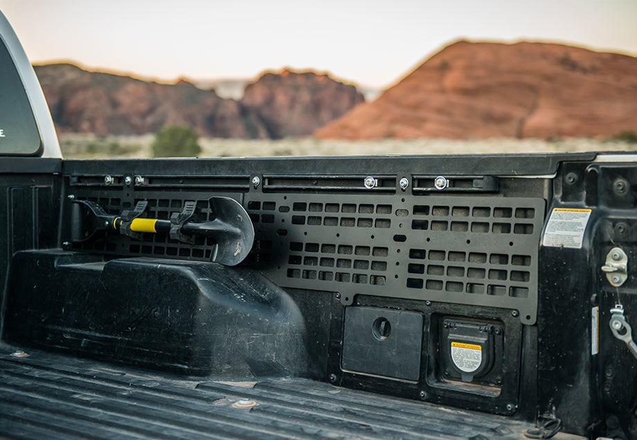 Toyota Tacoma bed molle panel with mounted off-road shovel, outdoor adventure setting