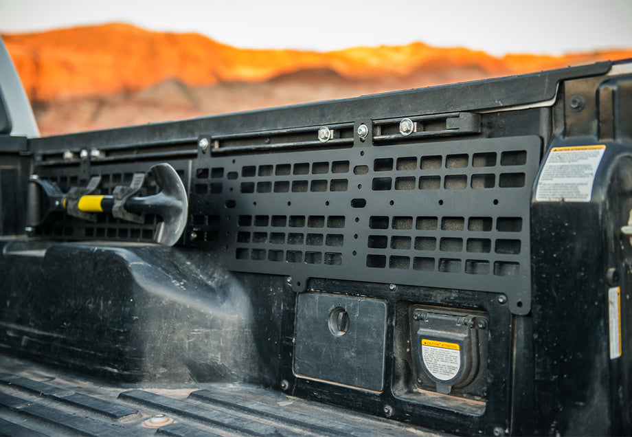 Toyota Tacoma bed with black molle panel and mounted tool for overlanding storage