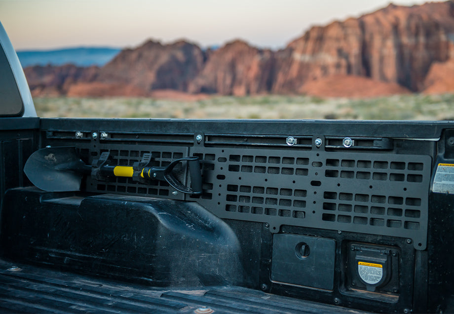 Toyota Tacoma bed Molle panel with mounted shovel, outdoor desert background