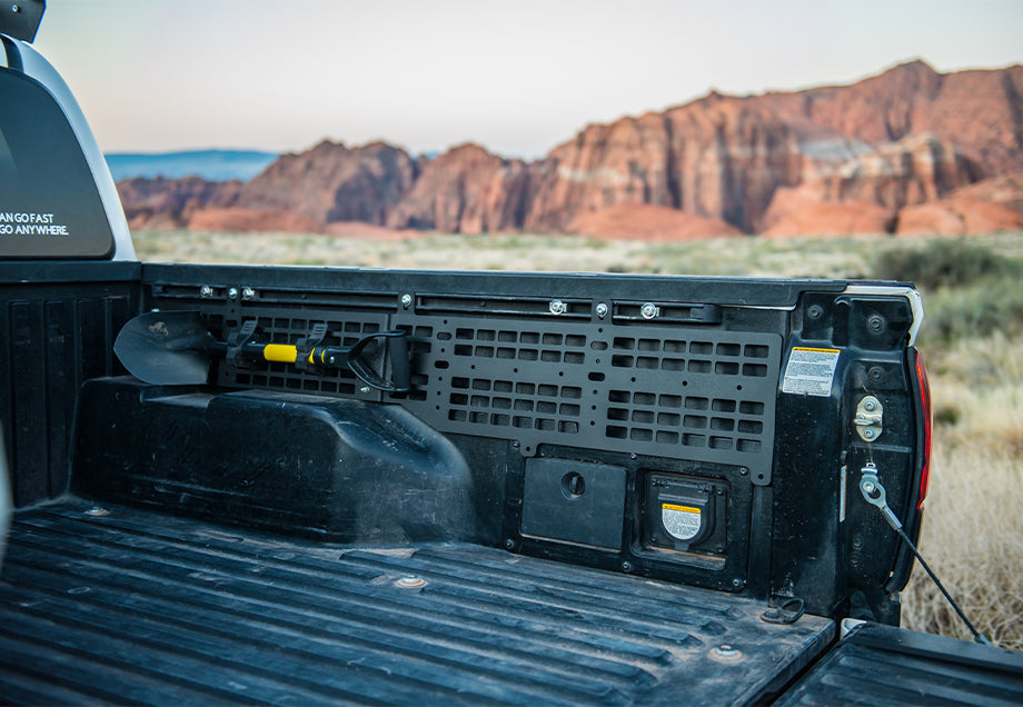 Toyota Tacoma bed with molle panel and mounted shovel, overlanding gear in desert landscape