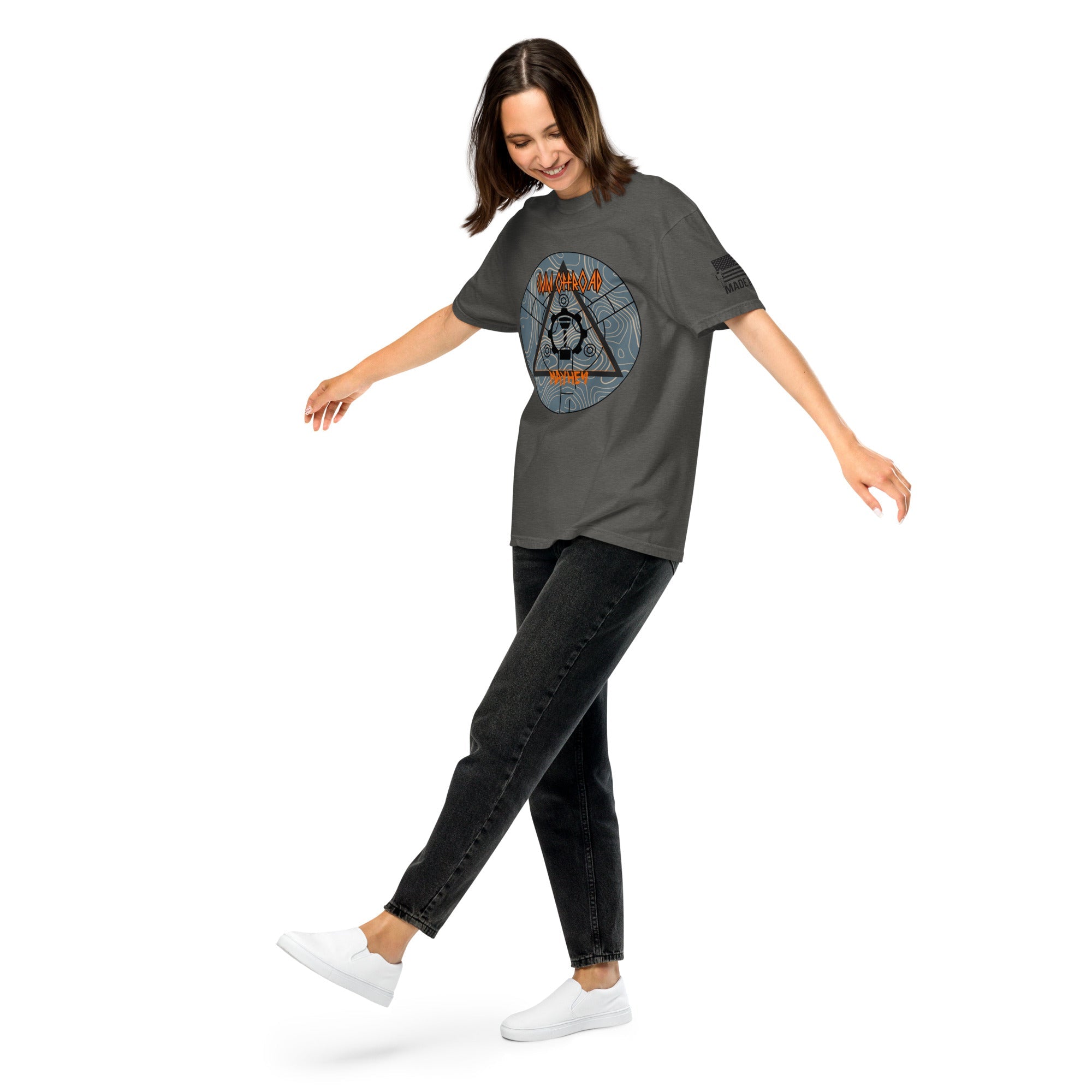 Woman wearing unisex pepper color heavyweight t-shirt with graphic, black jeans, and white shoes