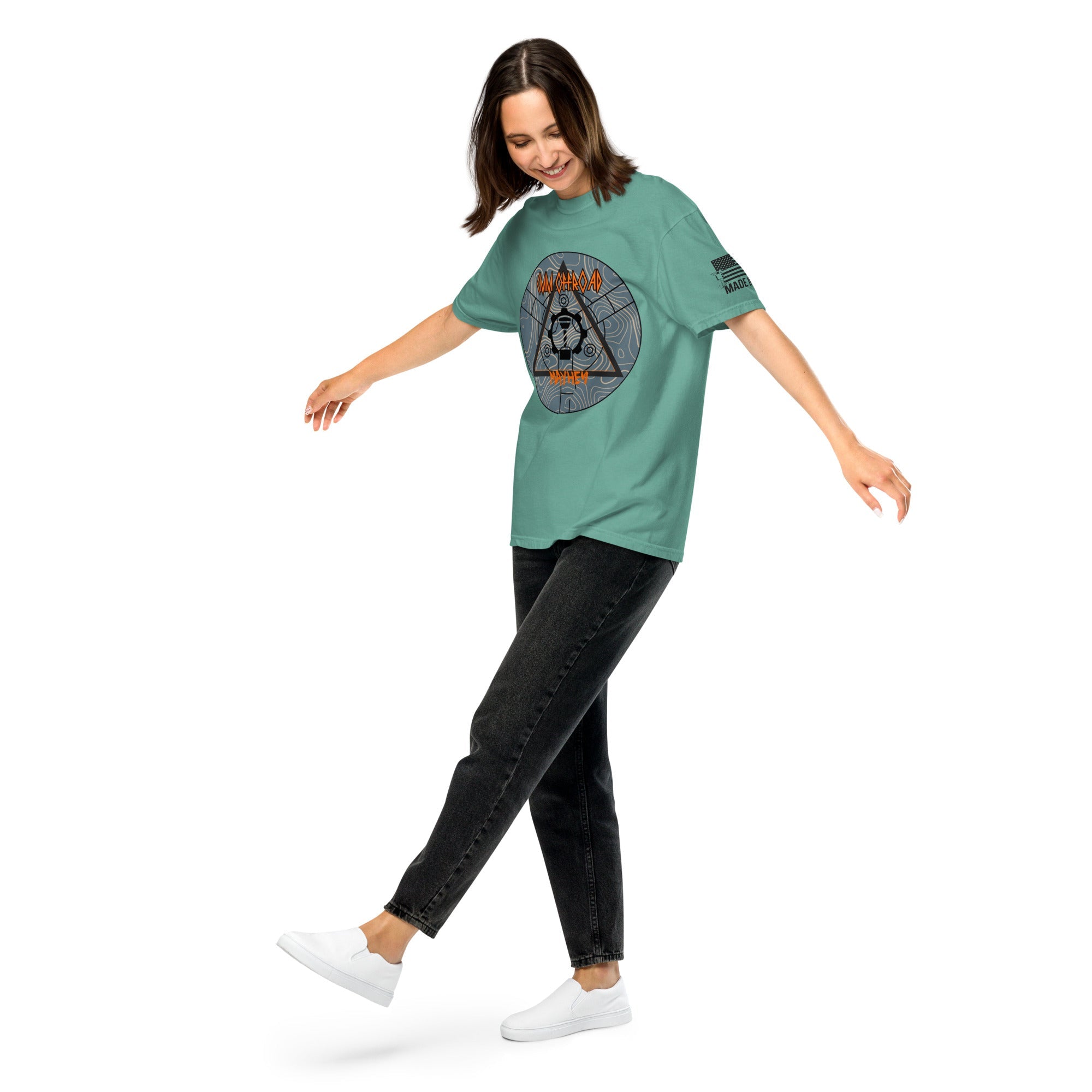 Woman wearing seafoam unisex heavyweight t-shirt with adventure graphic and black jeans