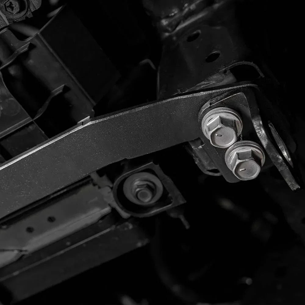 Closeup of heavy-duty steel bracket with bolts mounted on vehicle frame, overlanding accessory