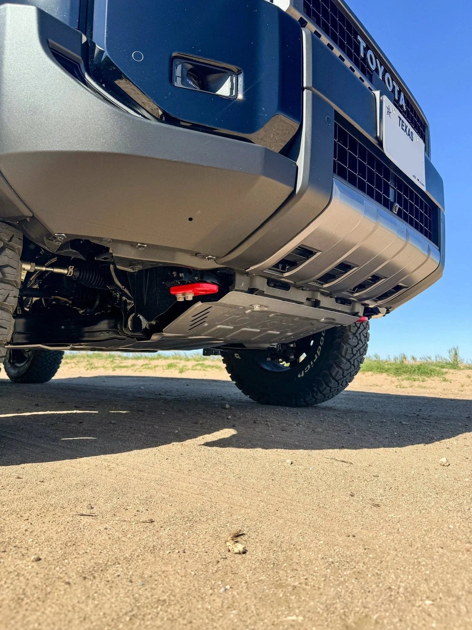Toyota Tundra front bumper and skid plate with off-road tires on sandy terrain