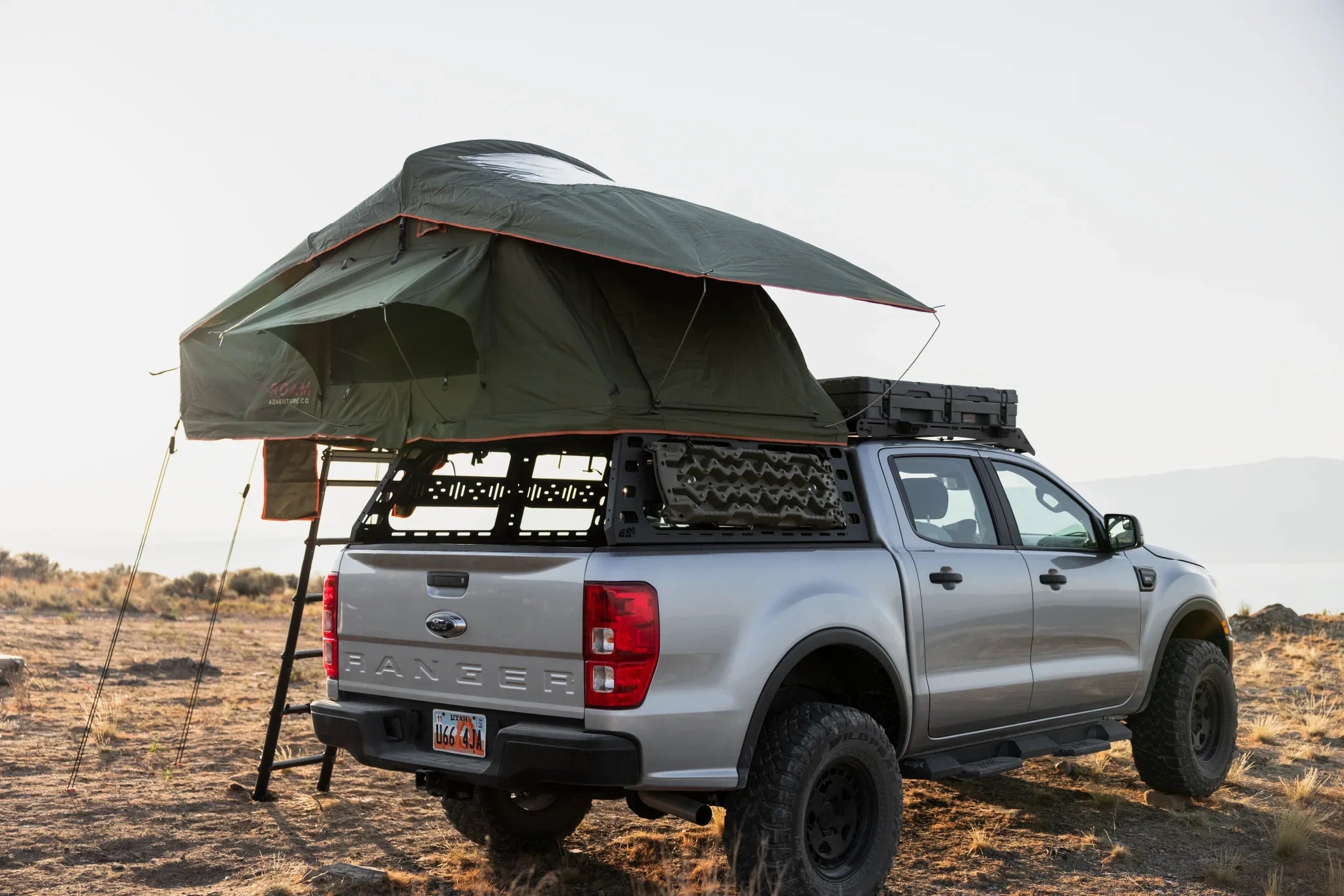 Ford Ranger pickup with rooftop tent, overland camping gear, parked on rugged terrain