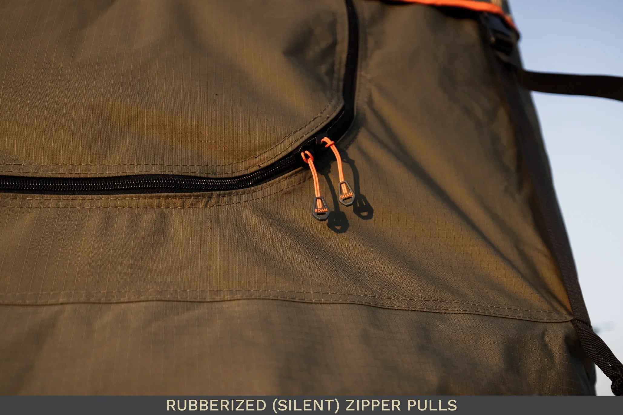 Close-up of rubberized silent zipper pulls on durable camping gear fabric