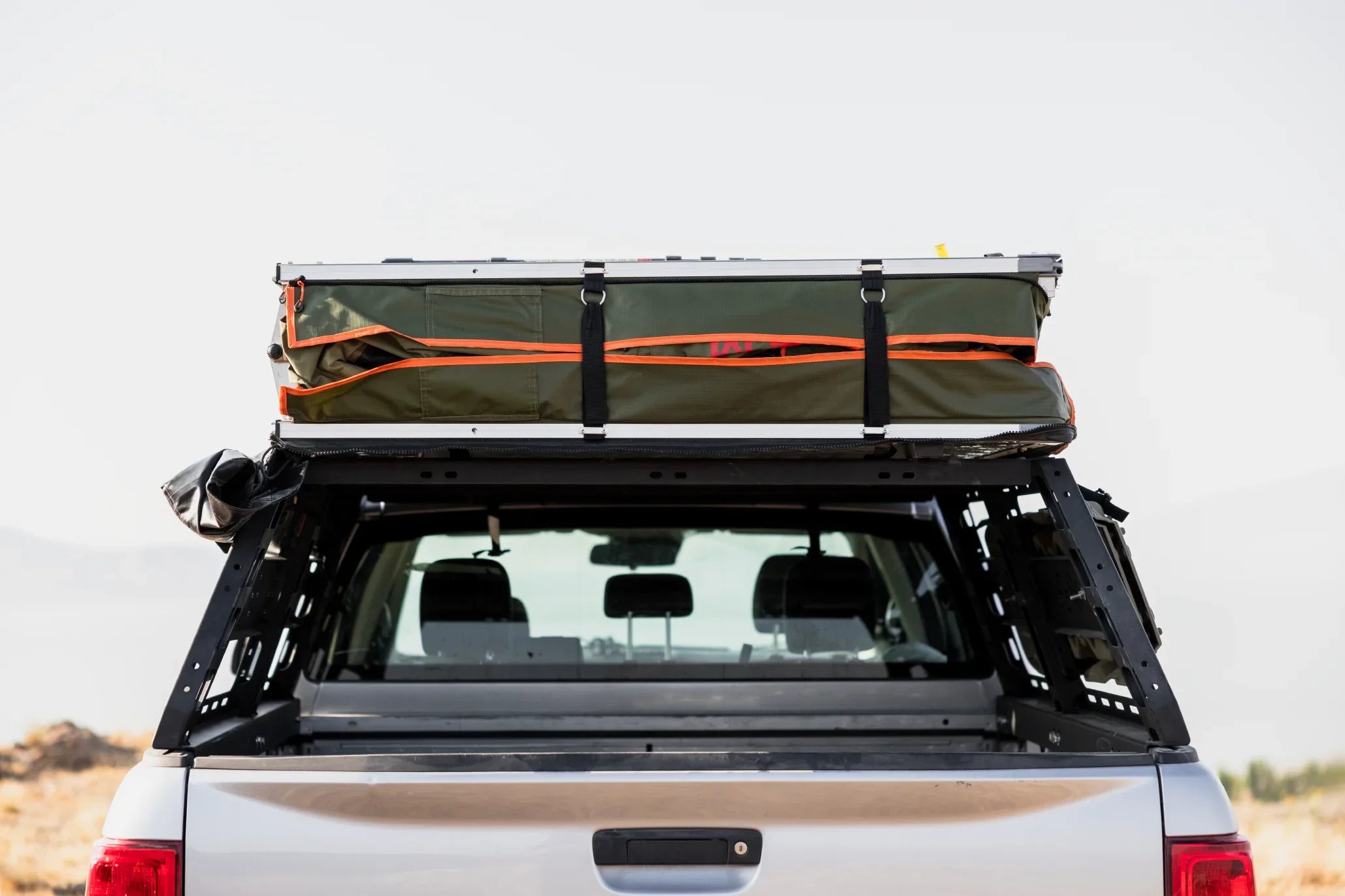 Overland rooftop tent packed on truck bed rack for camping and adventure gear