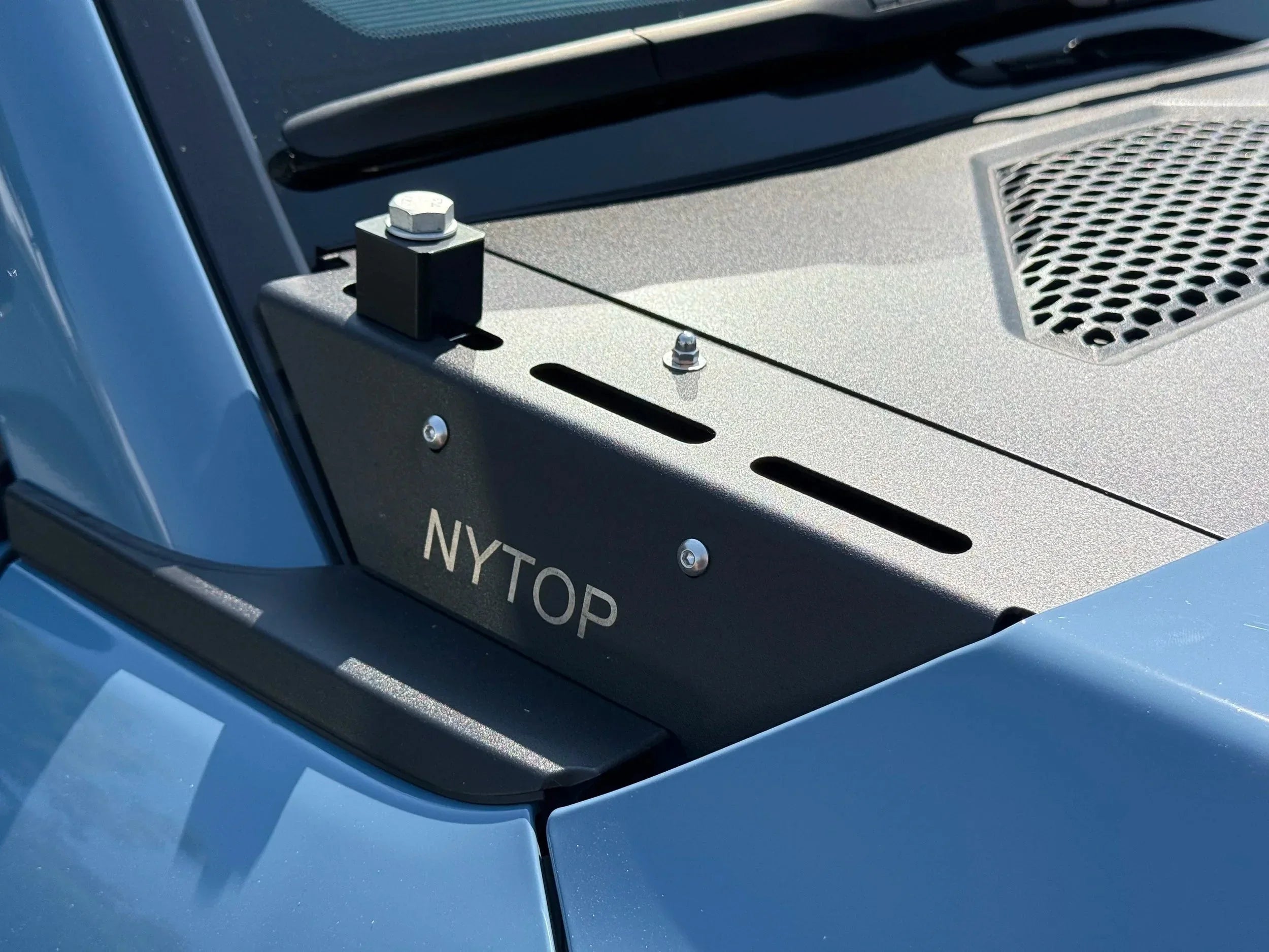 Close-up of NYTOP hood accessory bracket mounted on a blue off-road vehicle