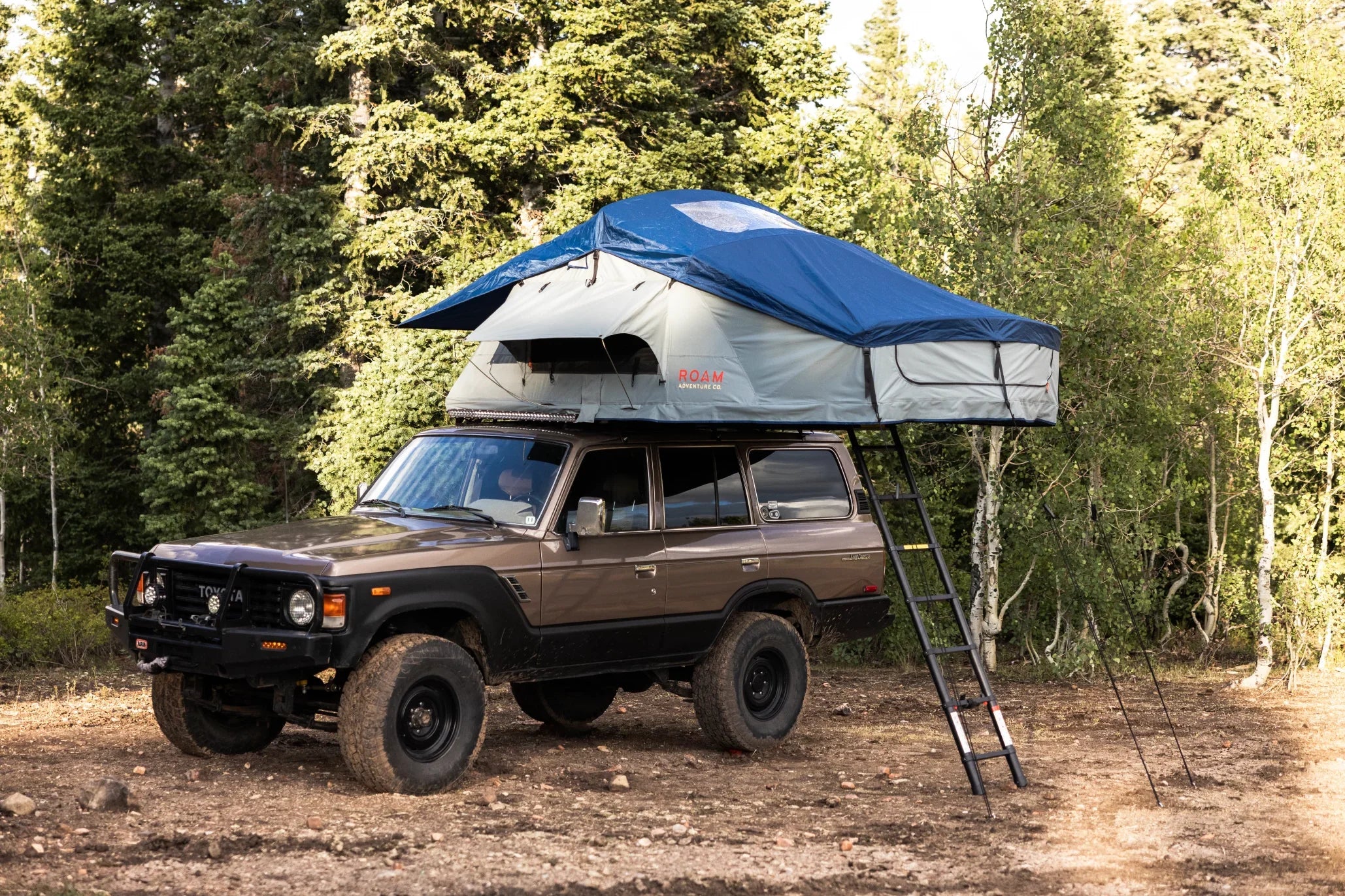 Rooftop tent mounted on off-road vehicle in forest, adventure camping gear setup